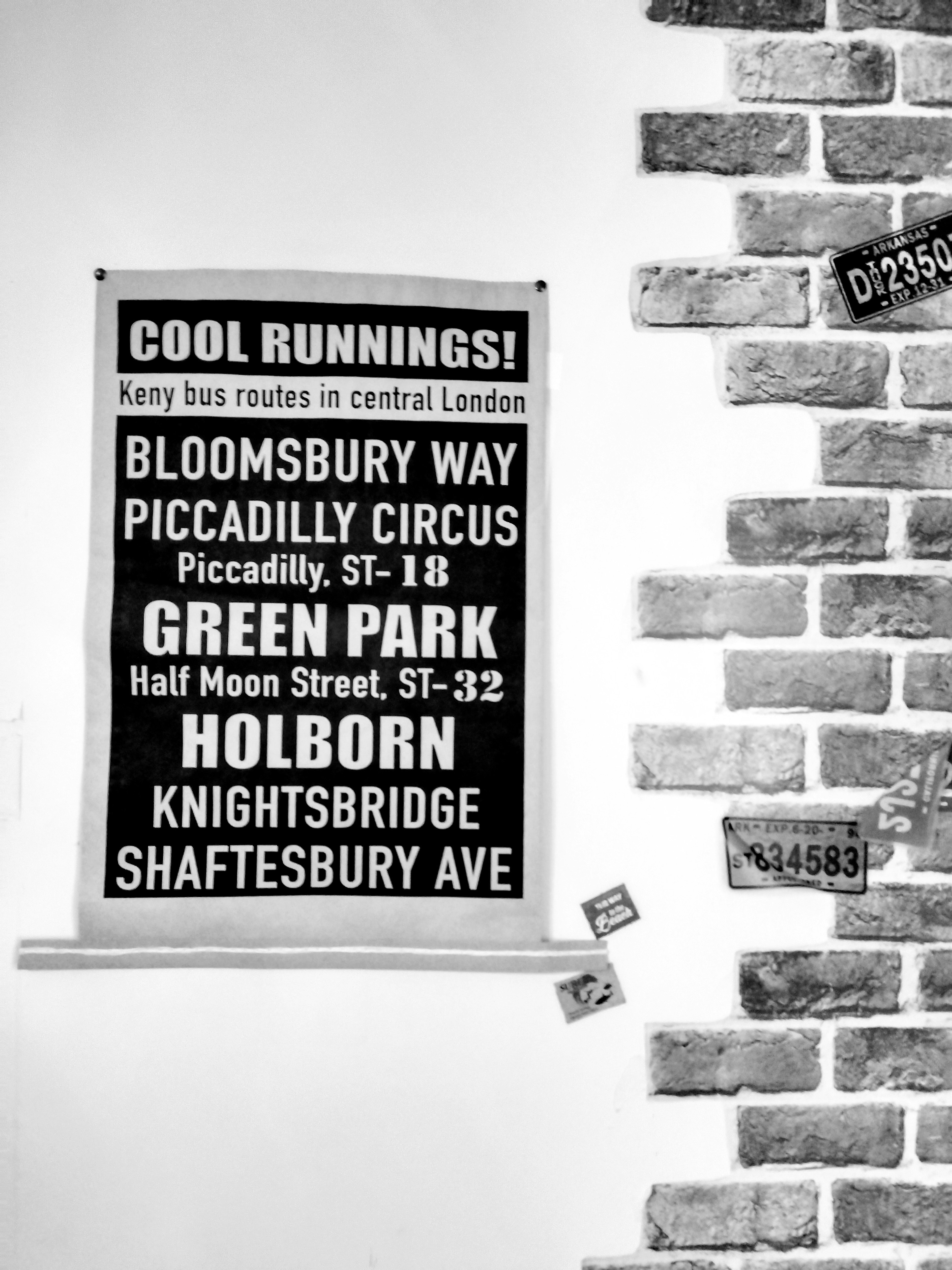 Cartel en blanco y negro que muestra nombres de calles de Londres colgado en una pared de ladrillo