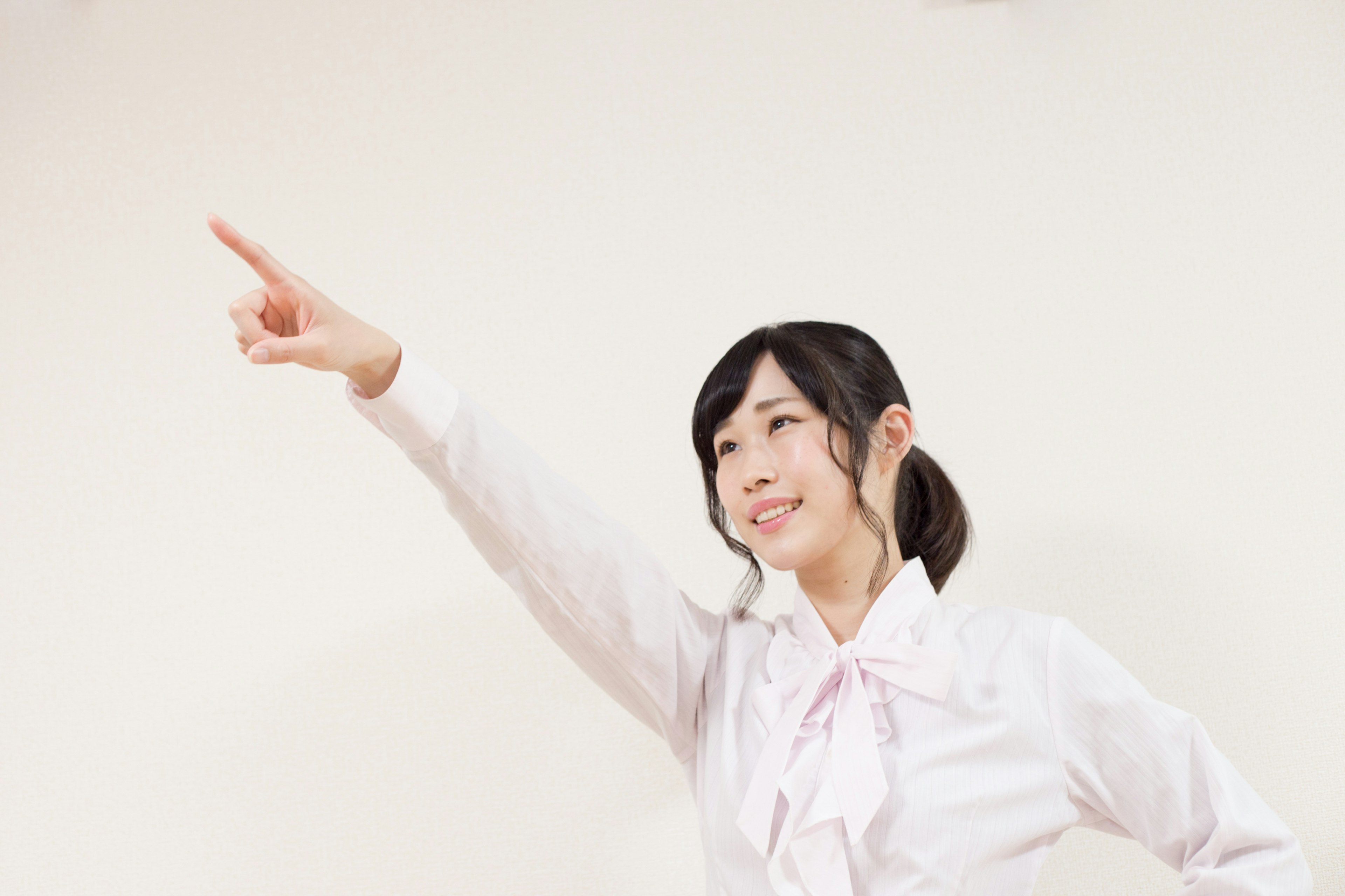 A woman in a white shirt pointing and smiling