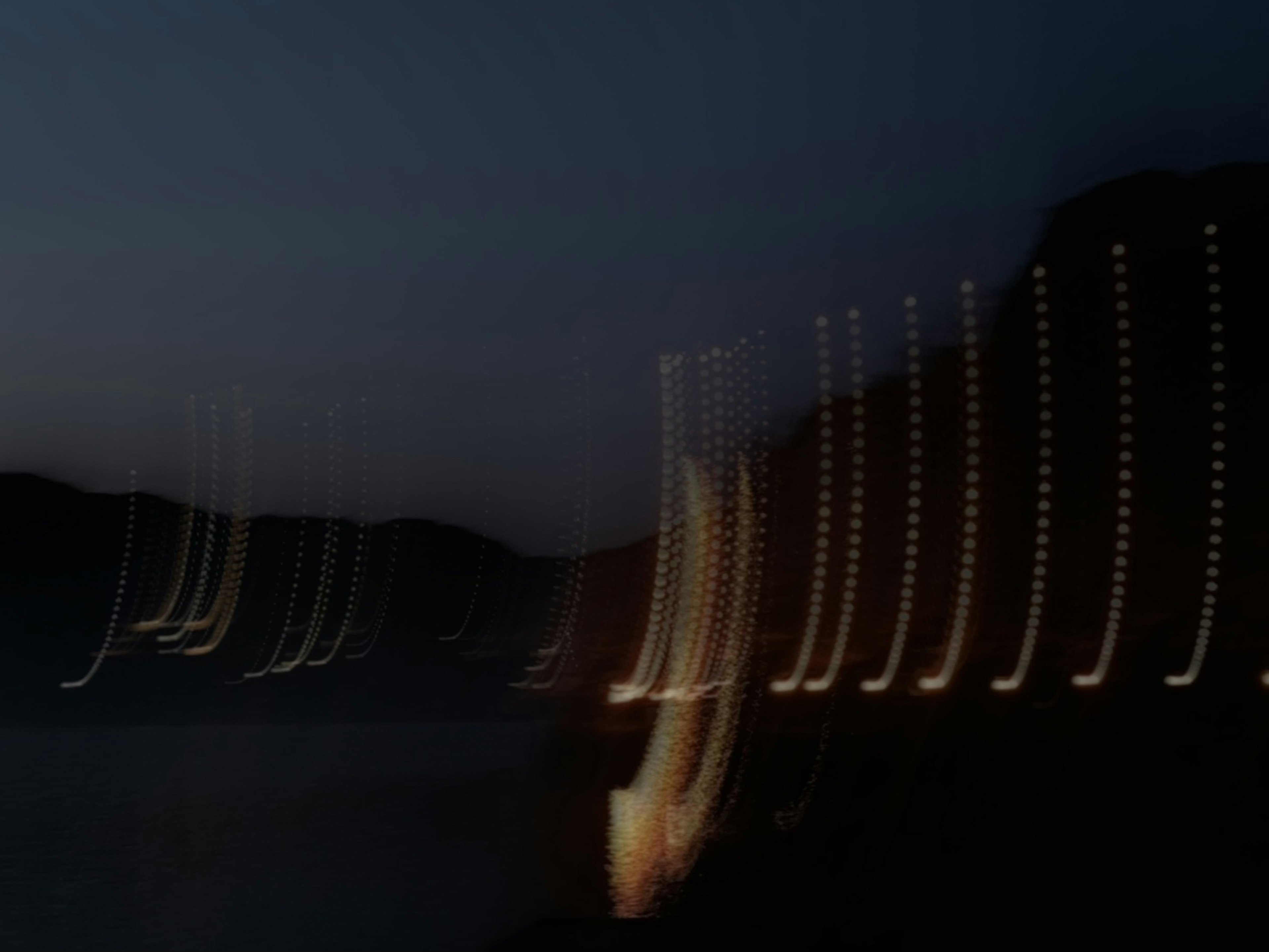 Blurred lights along a coastline at night with a dark sky