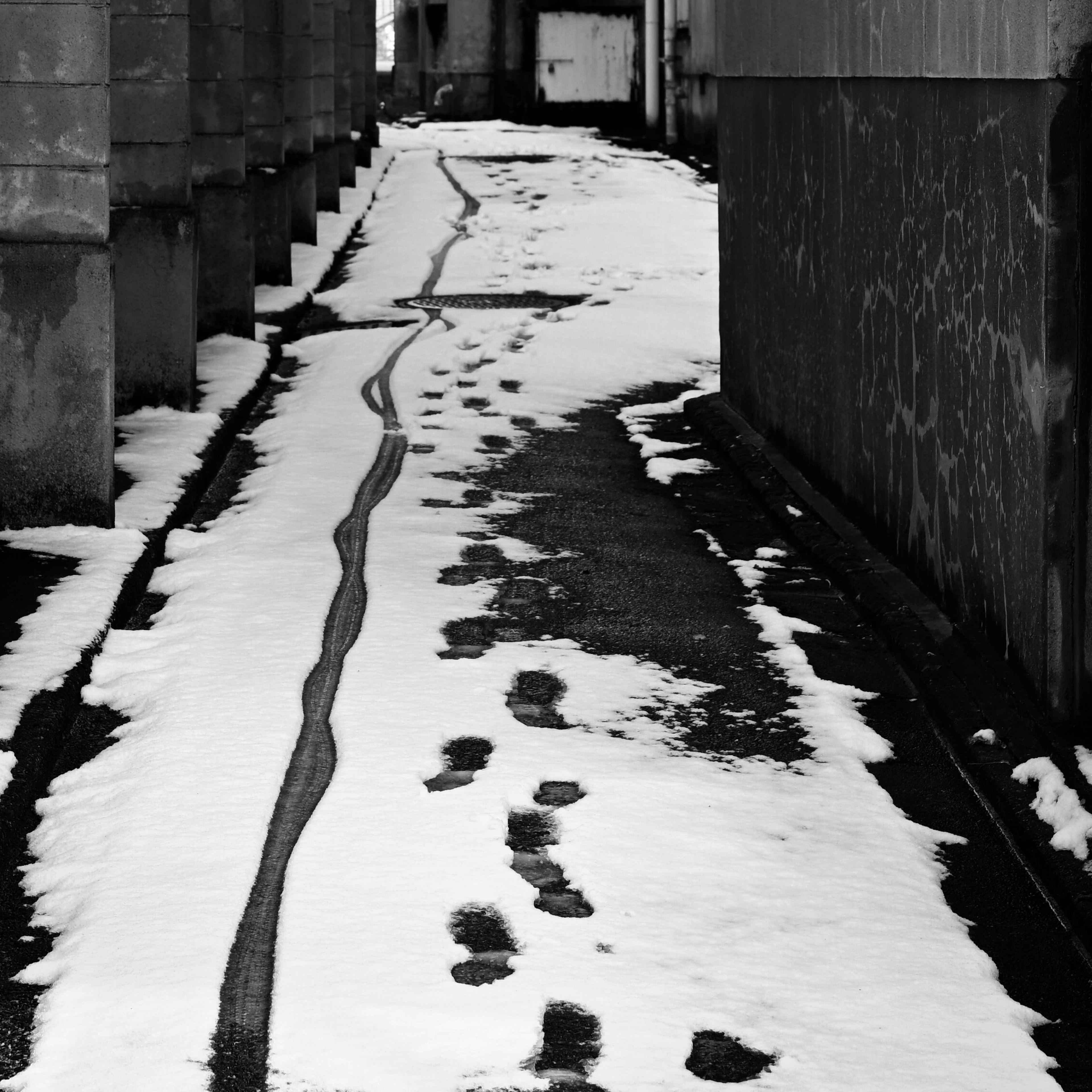 雪に覆われた小道に残る足跡とタイヤの跡