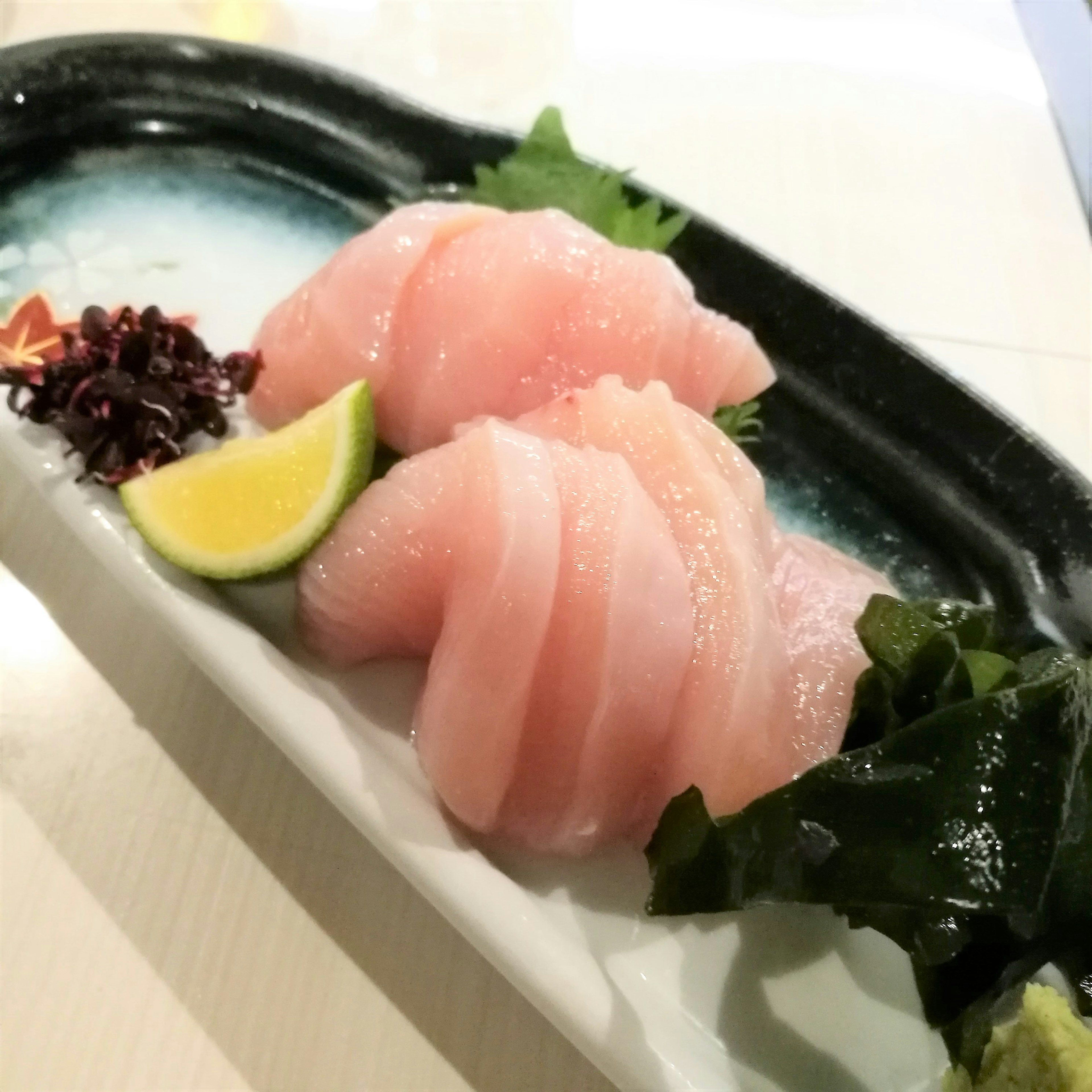 Plato de sashimi fresco con rodajas de pescado y lima