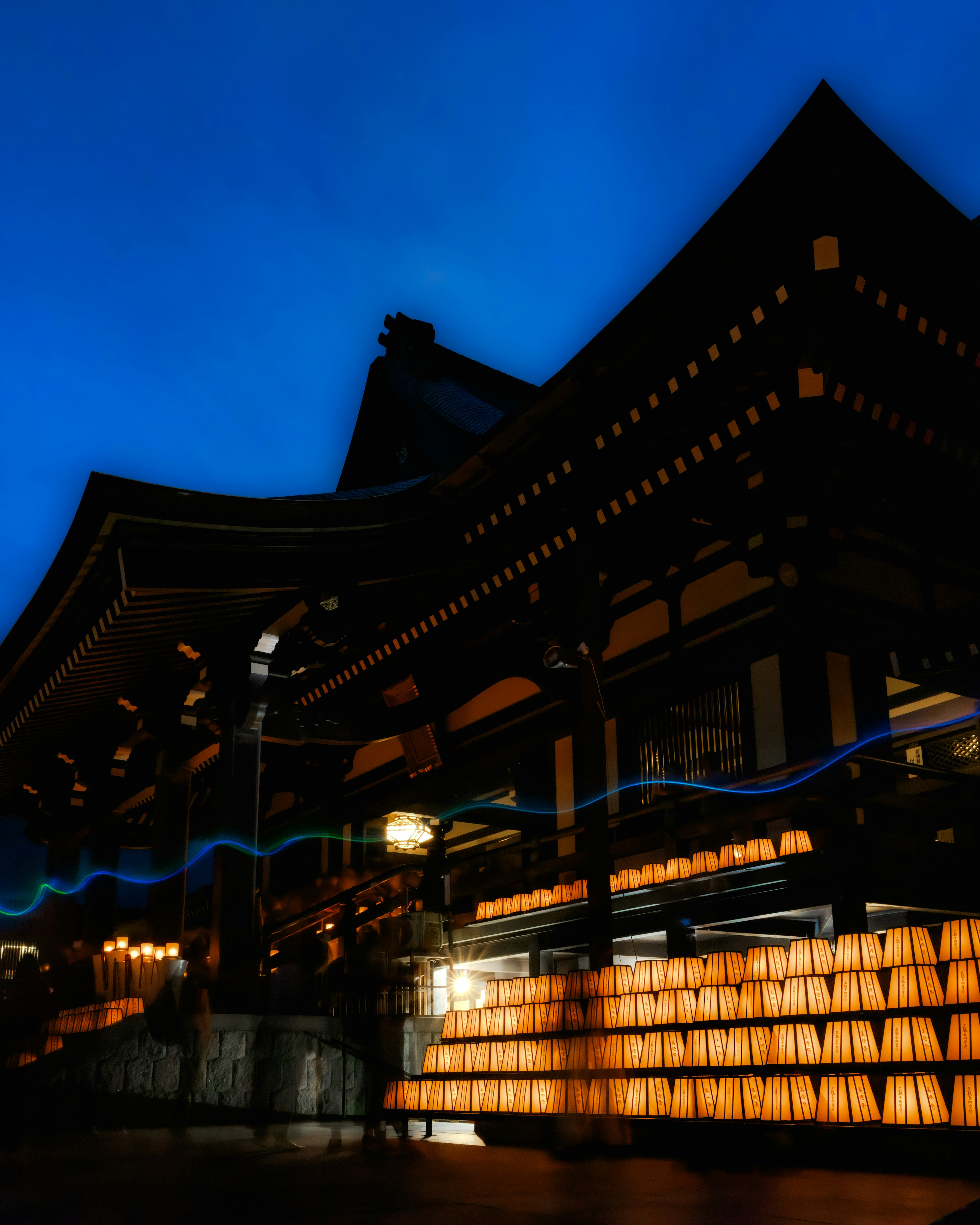 Bâtiment japonais traditionnel illuminé par des lanternes sous un ciel bleu