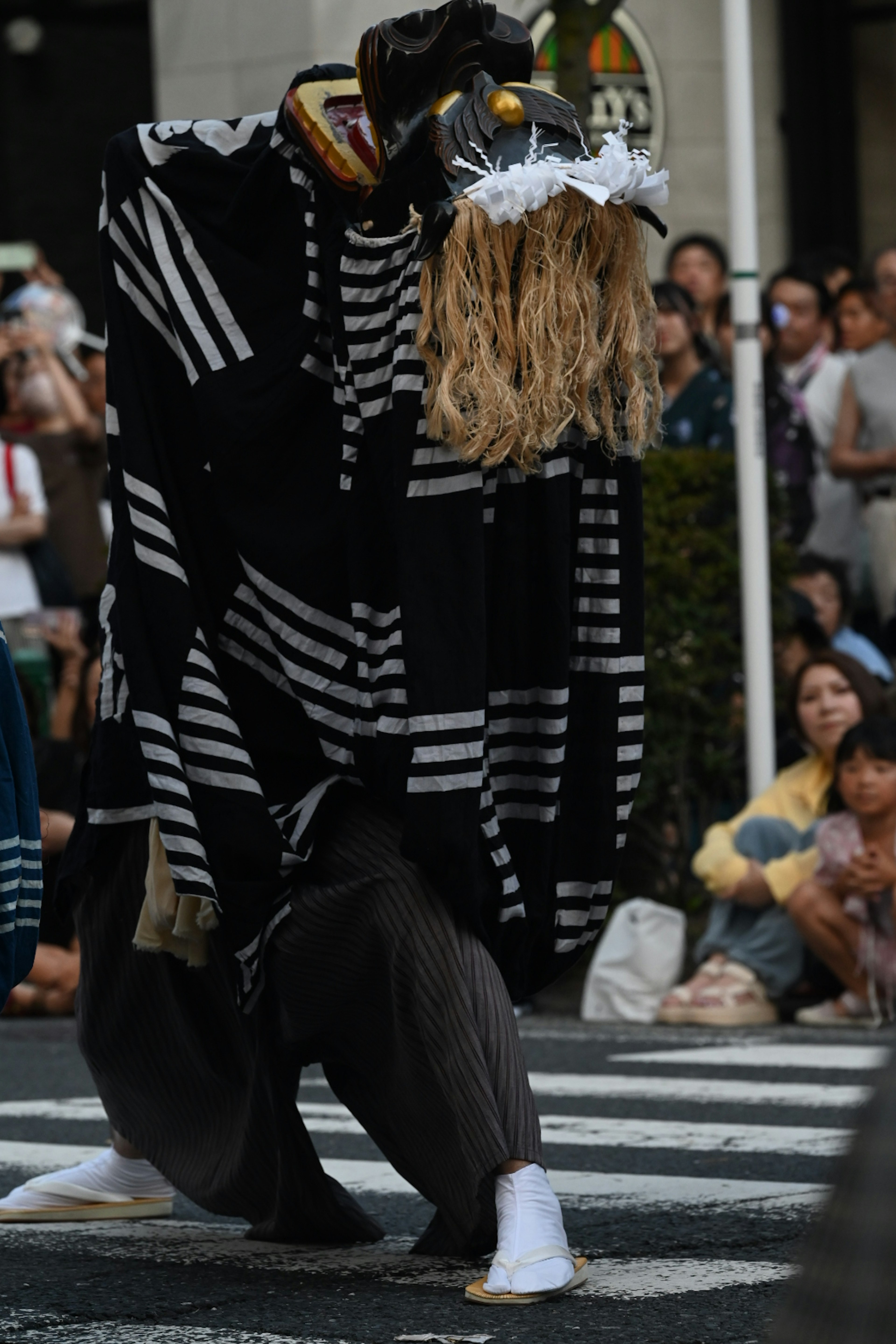 A traditional puppet performing in the street wearing a striped costume