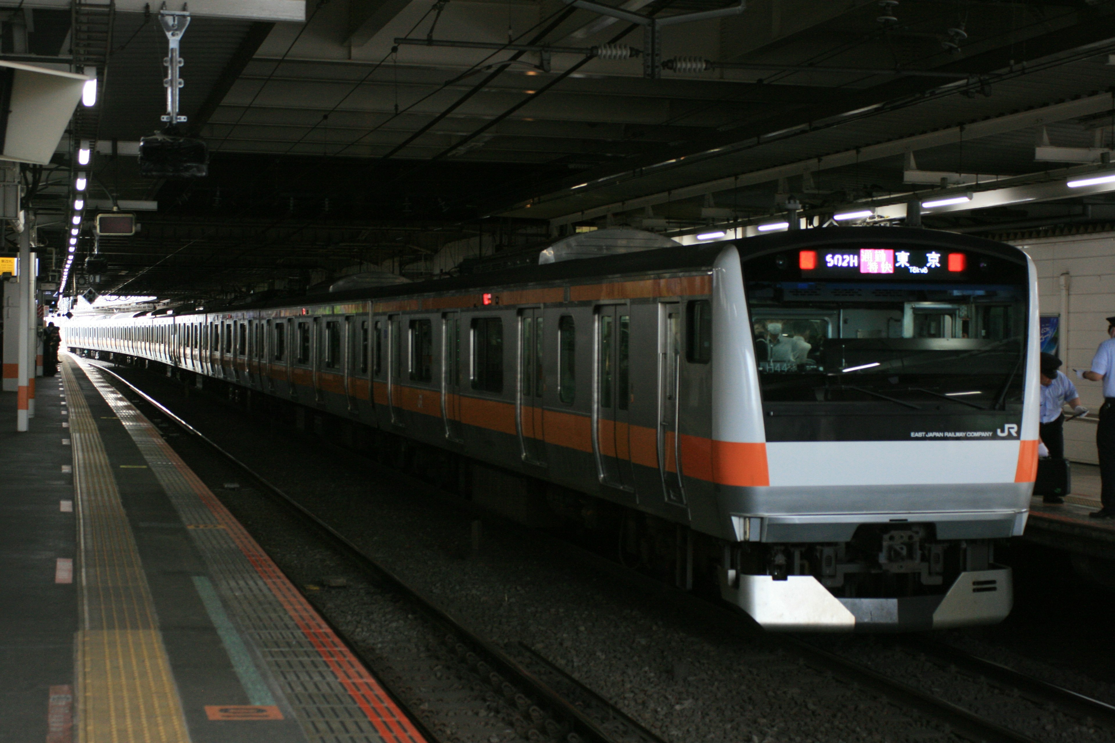 Tren naranja y plateado detenido en una estación subterránea