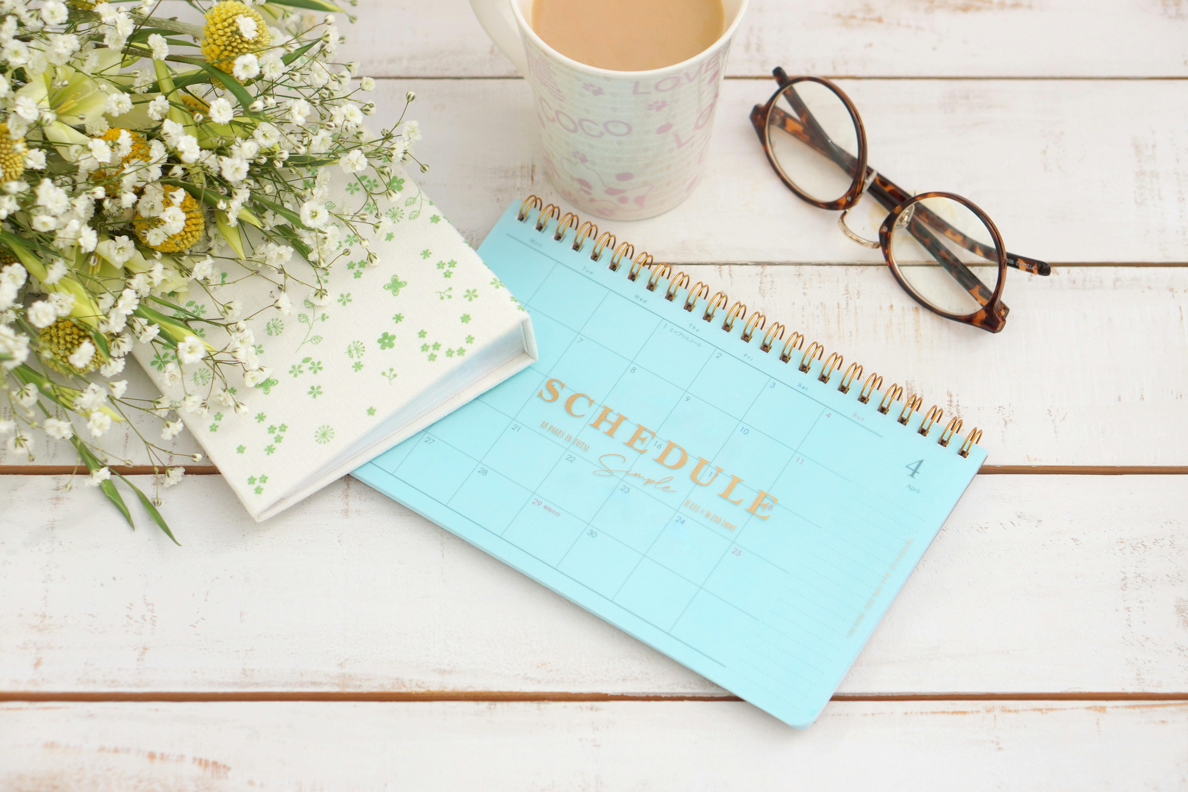 Una escena de escritorio con un calendario azul y un ramo de flores