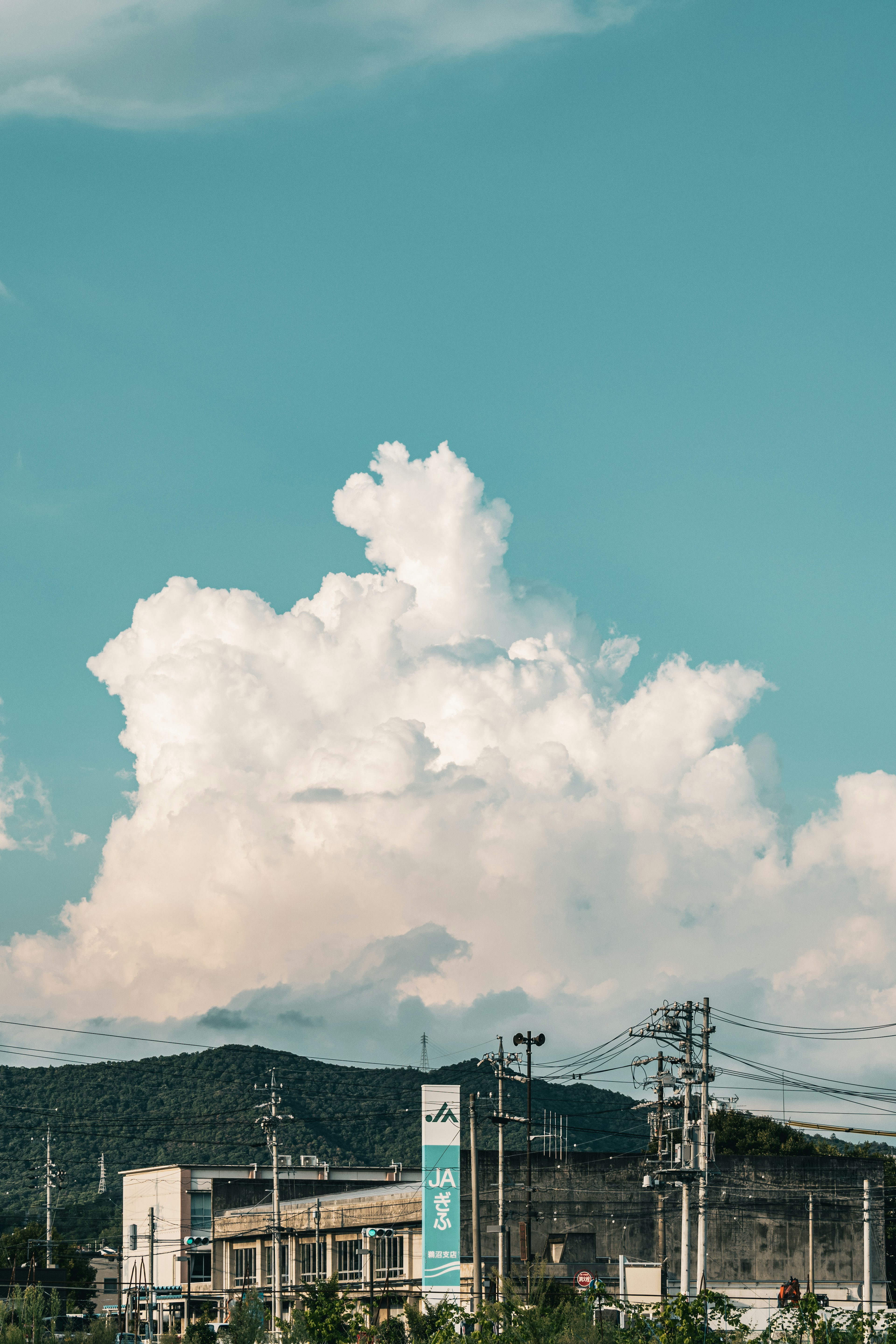 Eine große weiße Wolke schwebt in einem blauen Himmel mit Bergen im Hintergrund