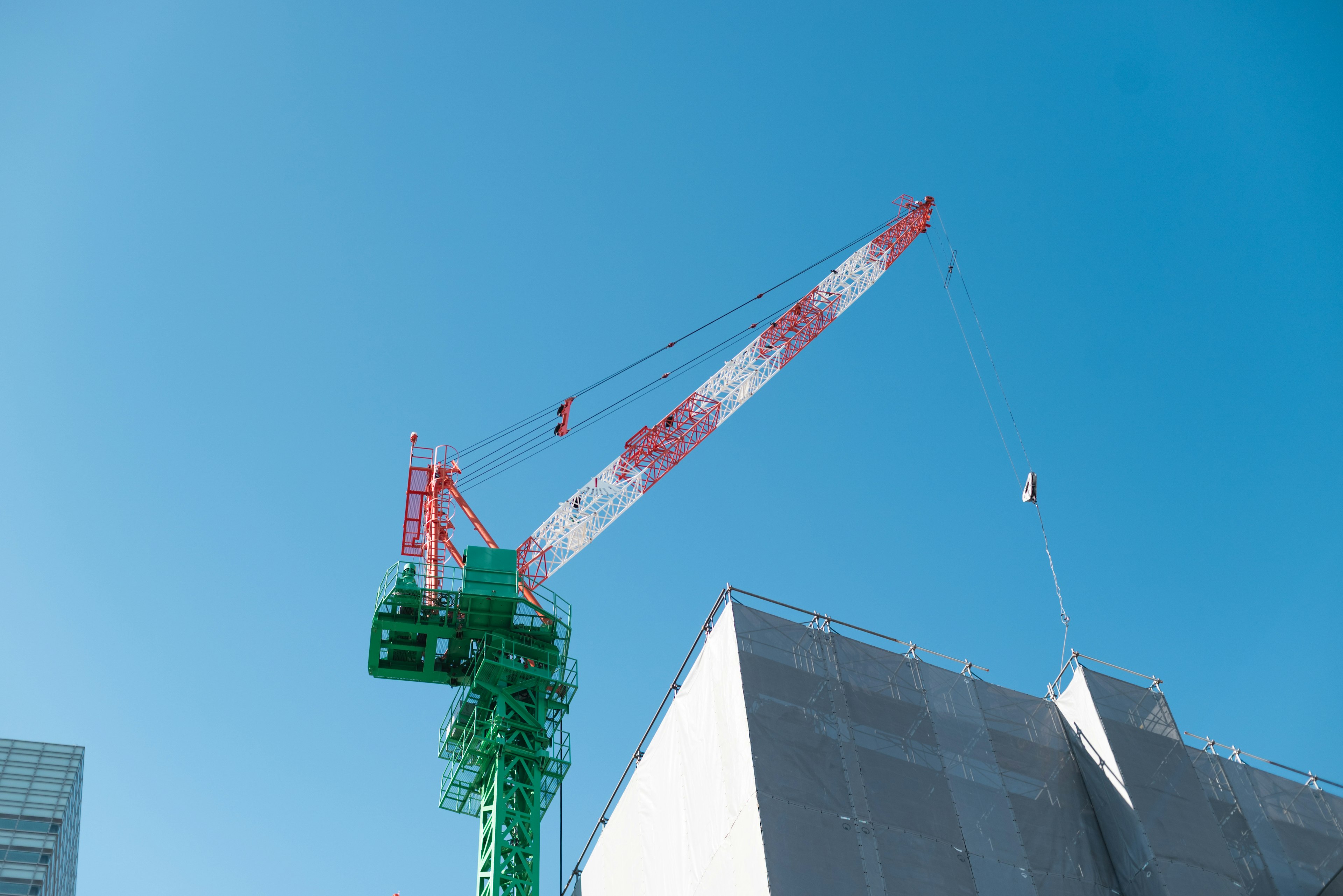 Grúa de construcción que se eleva sobre un edificio bajo un cielo azul claro