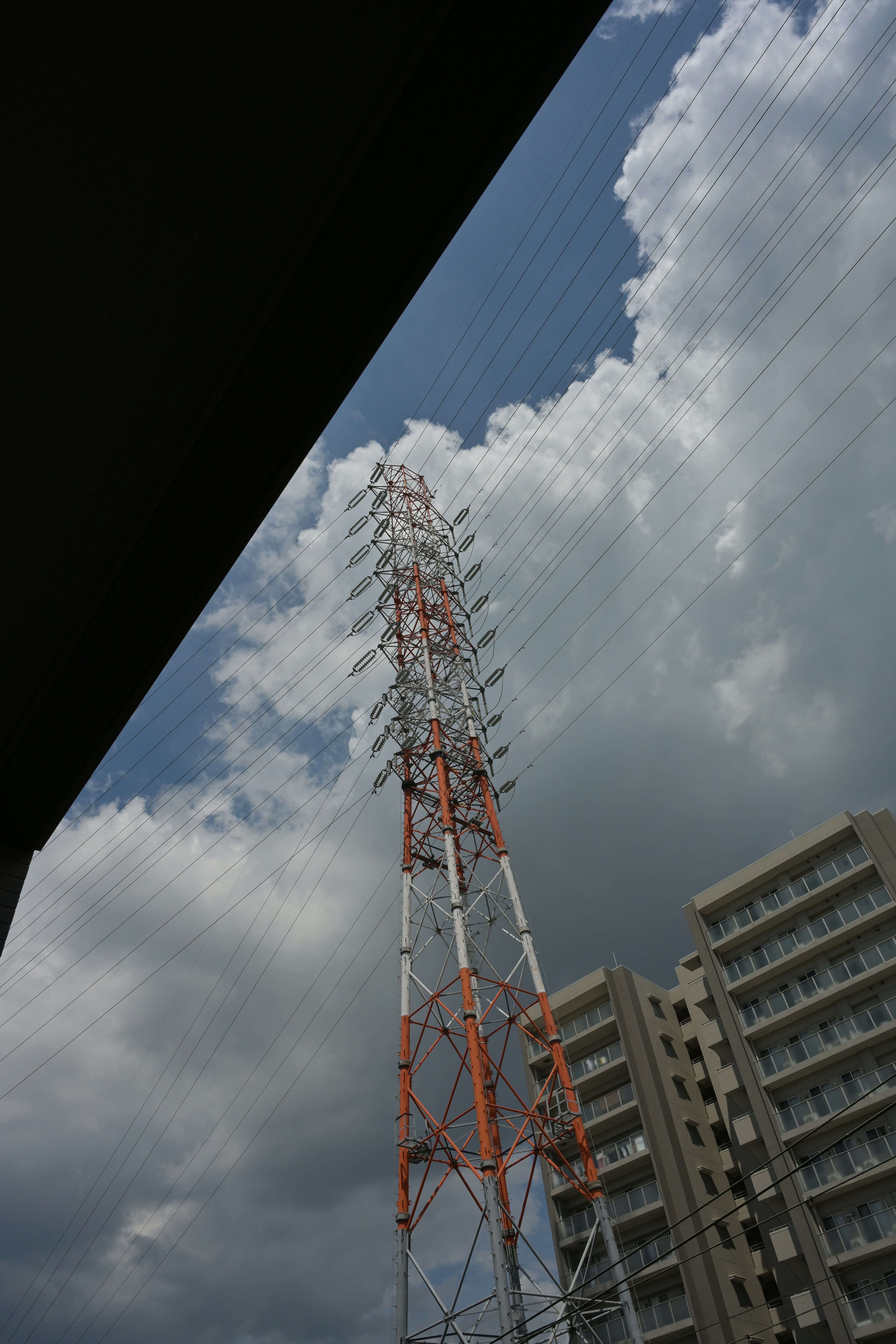 在藍天和雲層下的通信塔與附近建築的圖像