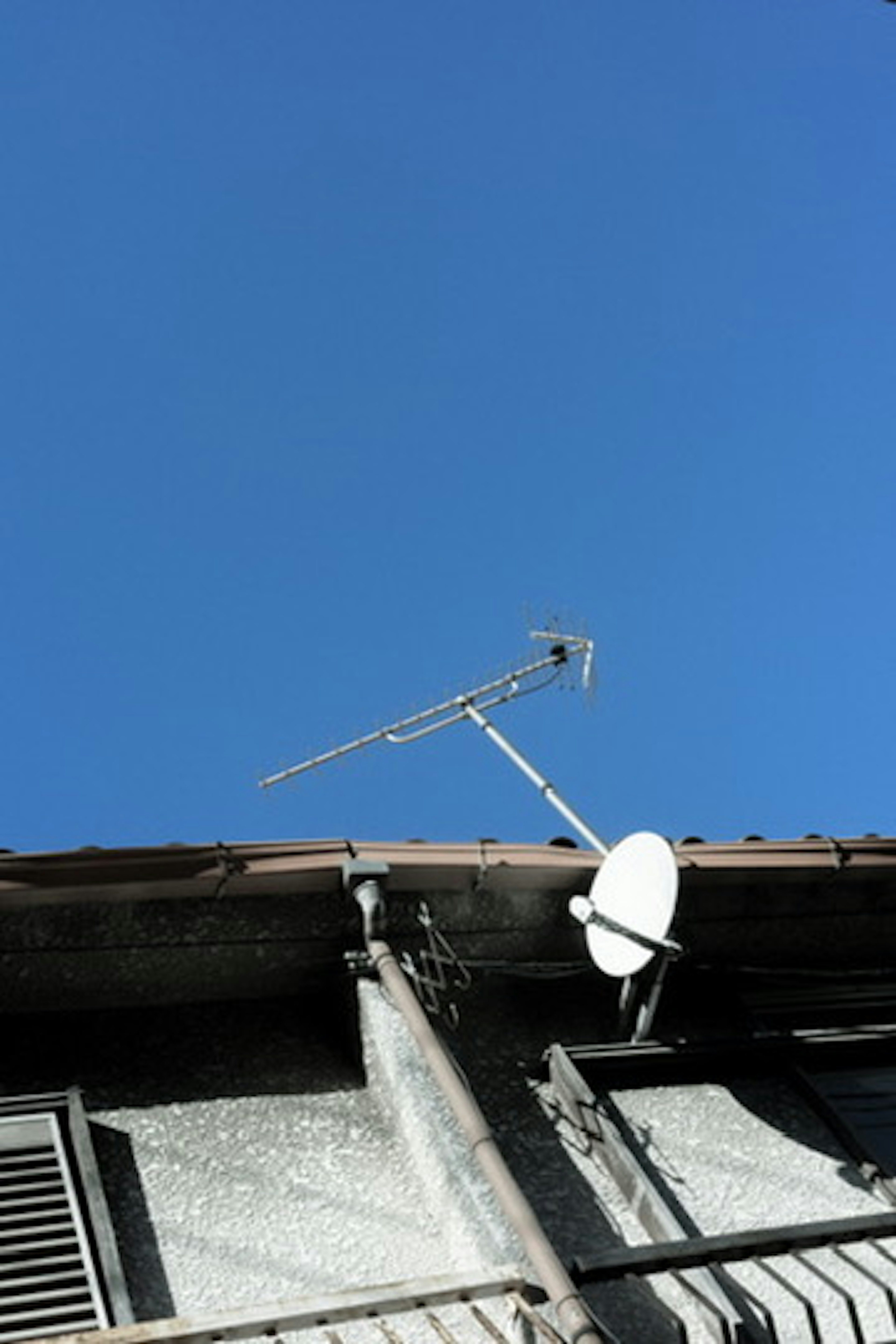 Antenna and satellite system on a roof under a blue sky