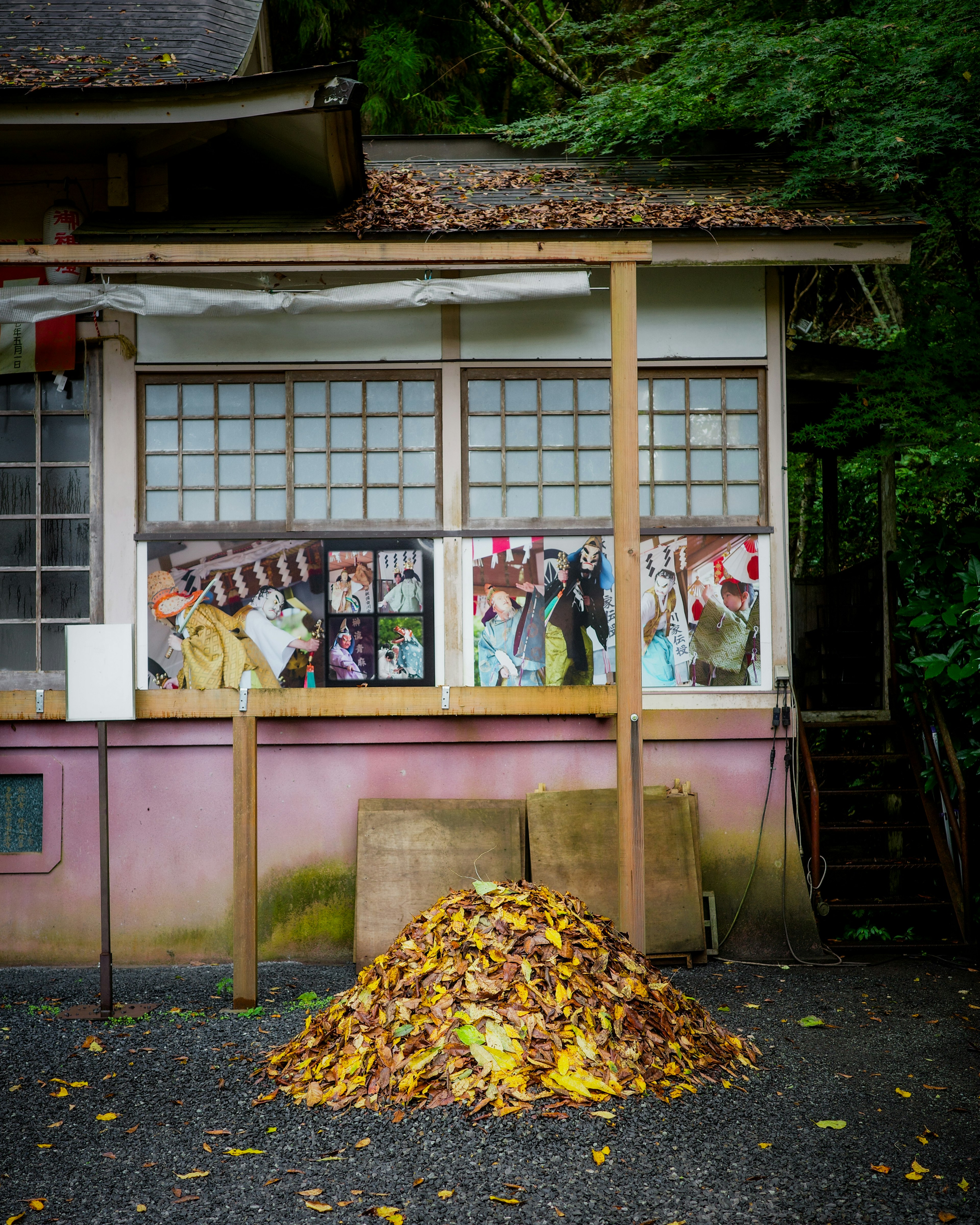 古い建物の前に積まれた落ち葉と窓にかかるポスター