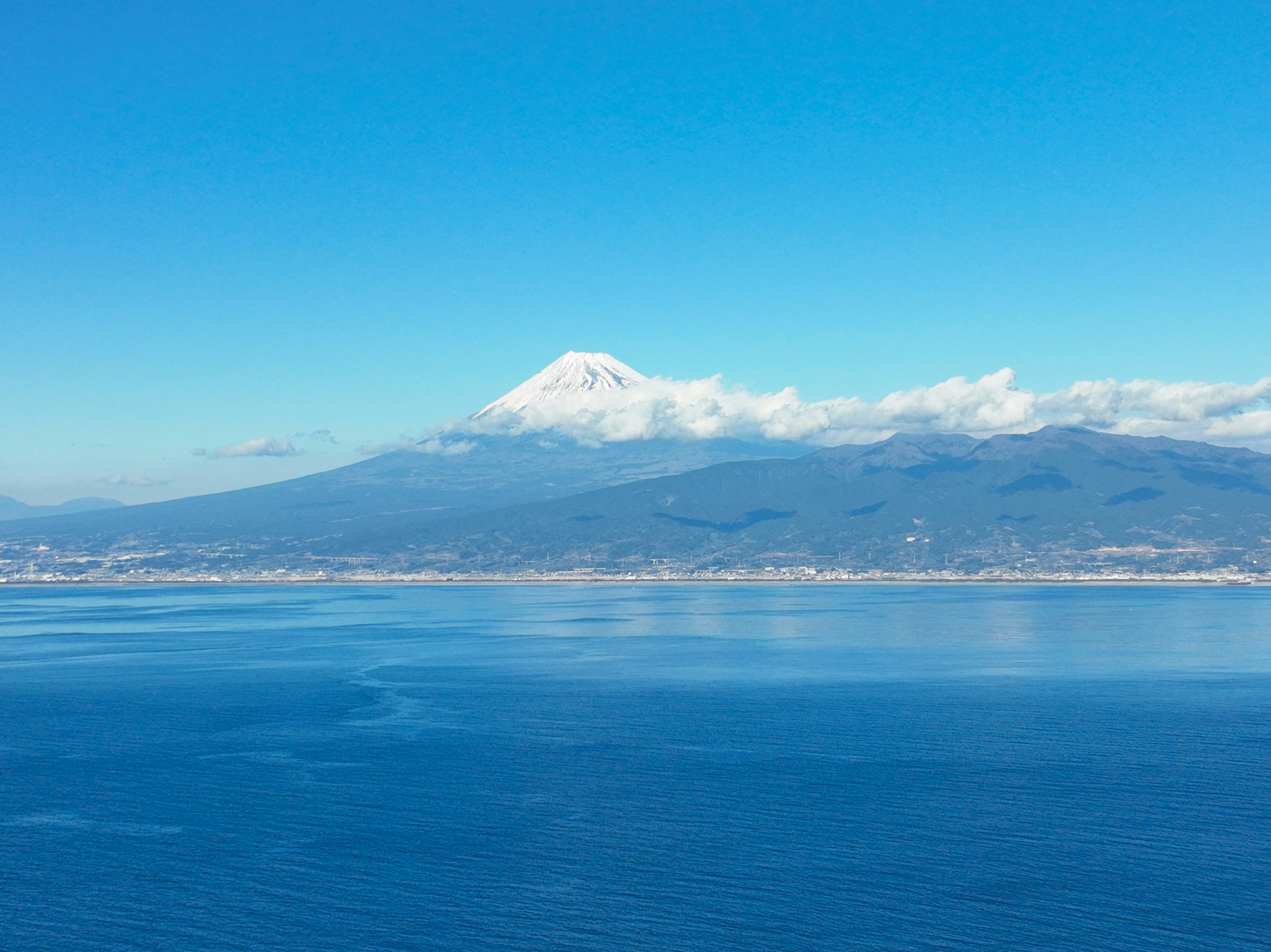 青い空と海に囲まれた雪をかぶった山