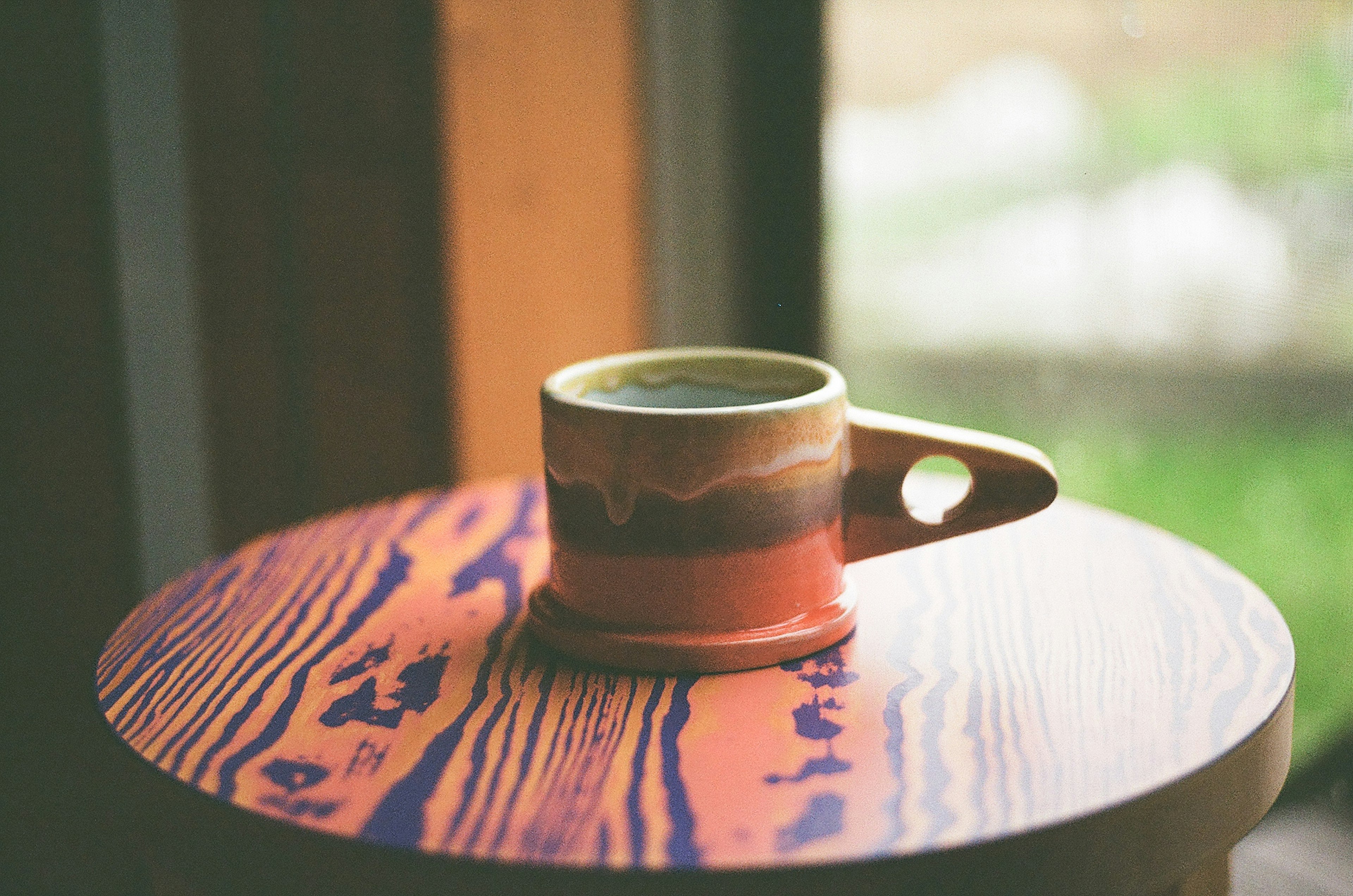 Tasse en céramique colorée posée sur une table en bois