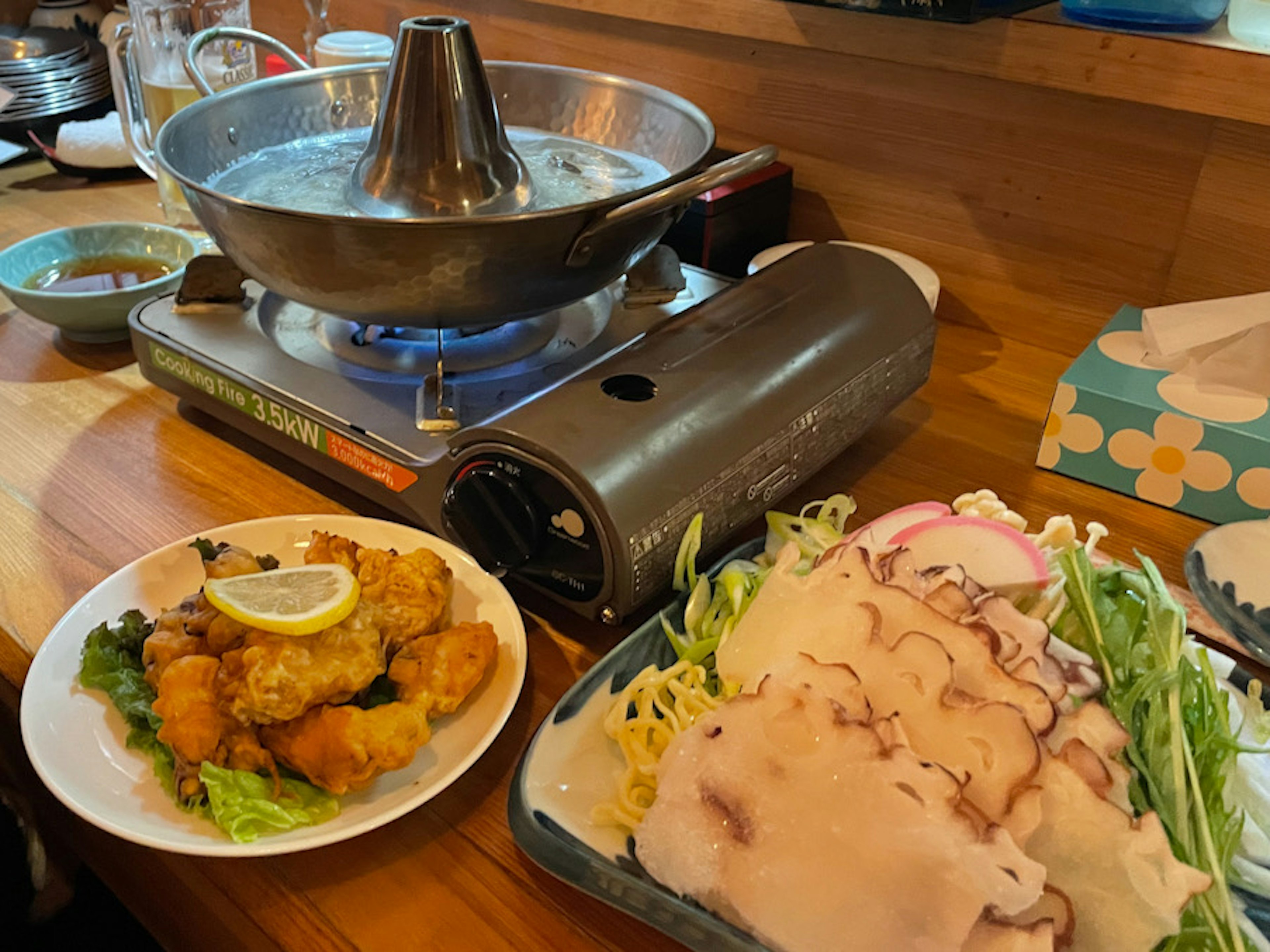 Ensemble de pot chaud et de nourriture frite sur une table avec des ingrédients frais et une soupe chaude