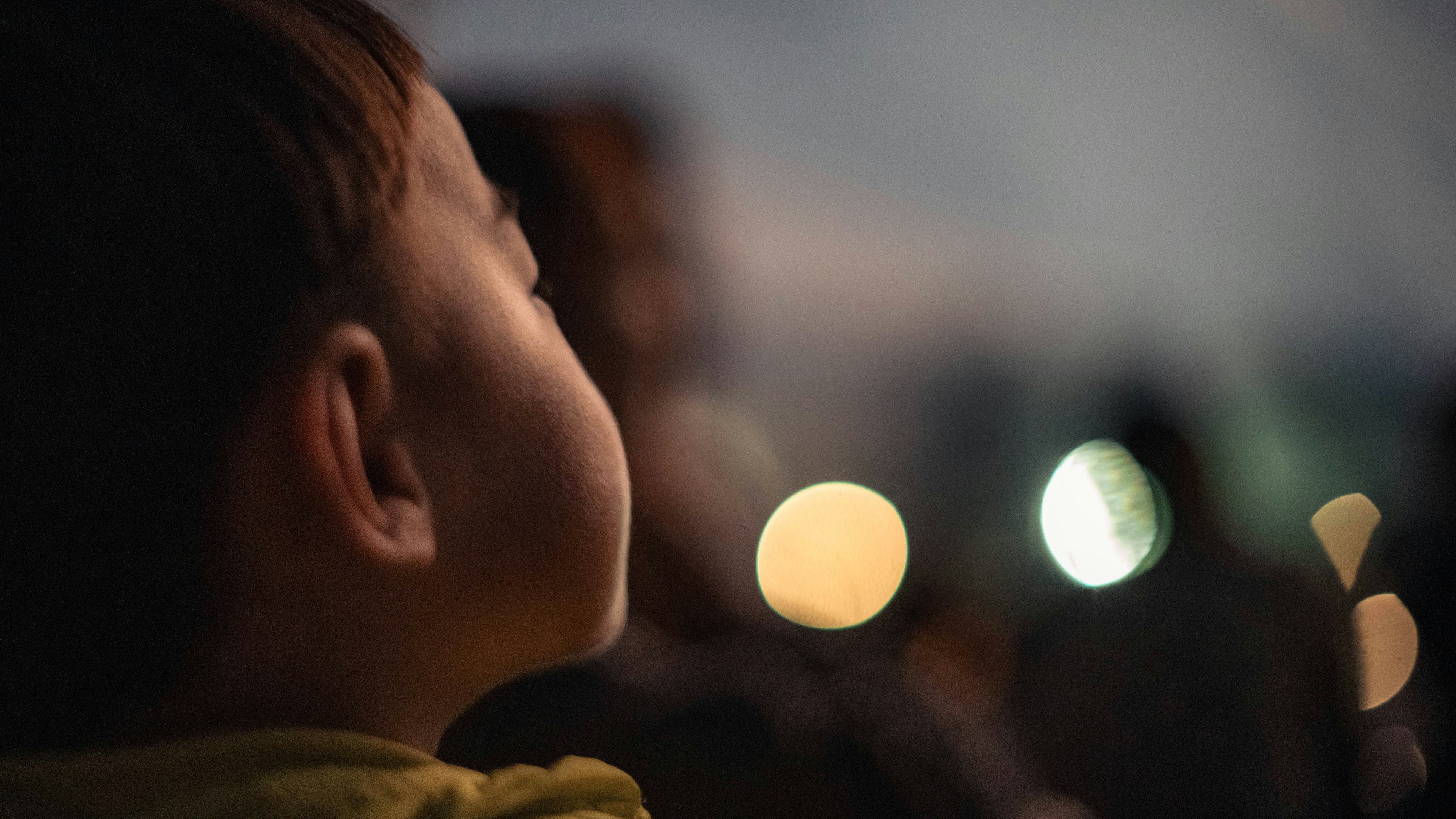 Profil anak yang melihat ke langit malam dengan cahaya kabur