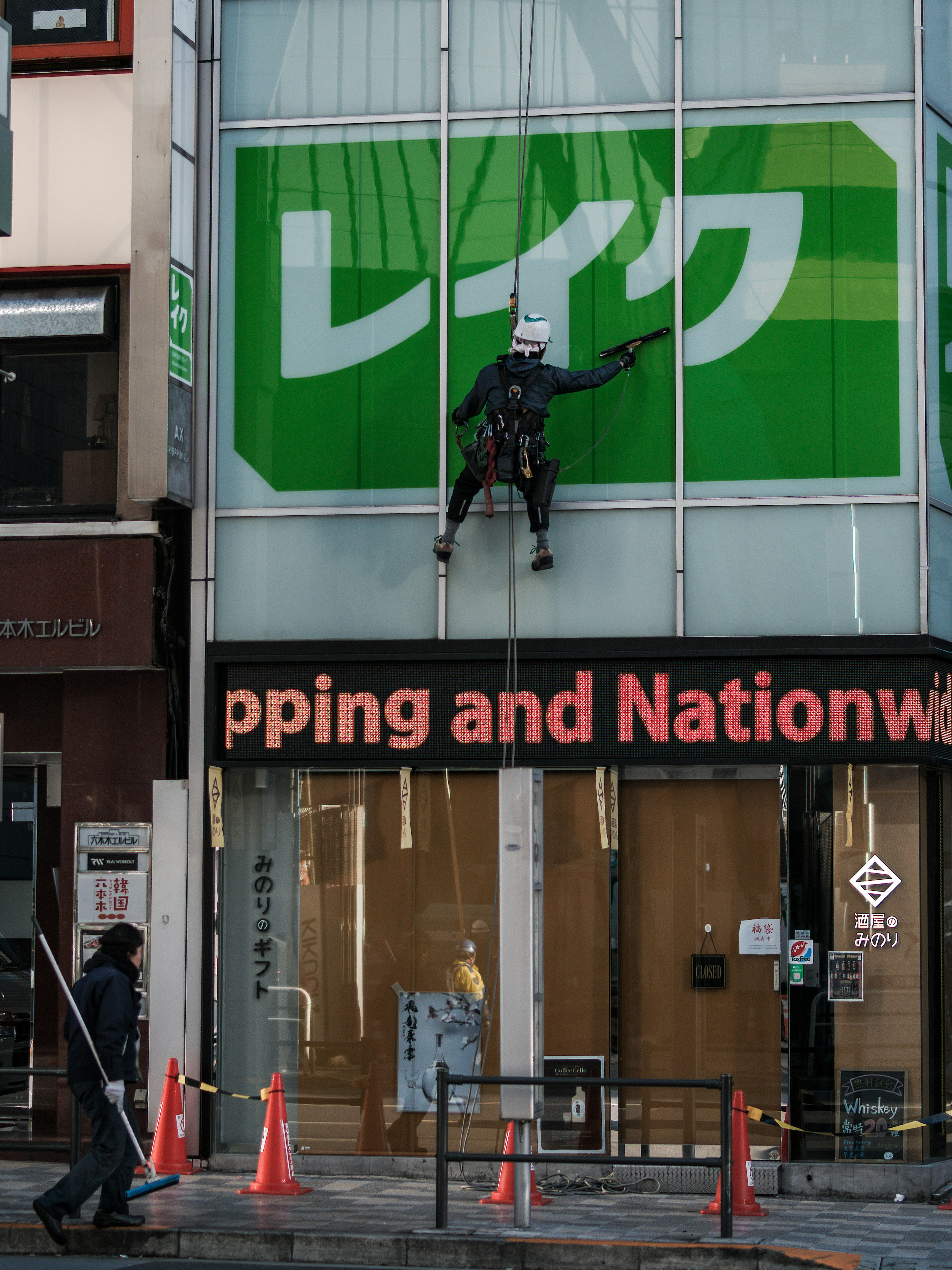 Un trabajador limpiando una ventana de edificio en un entorno urbano