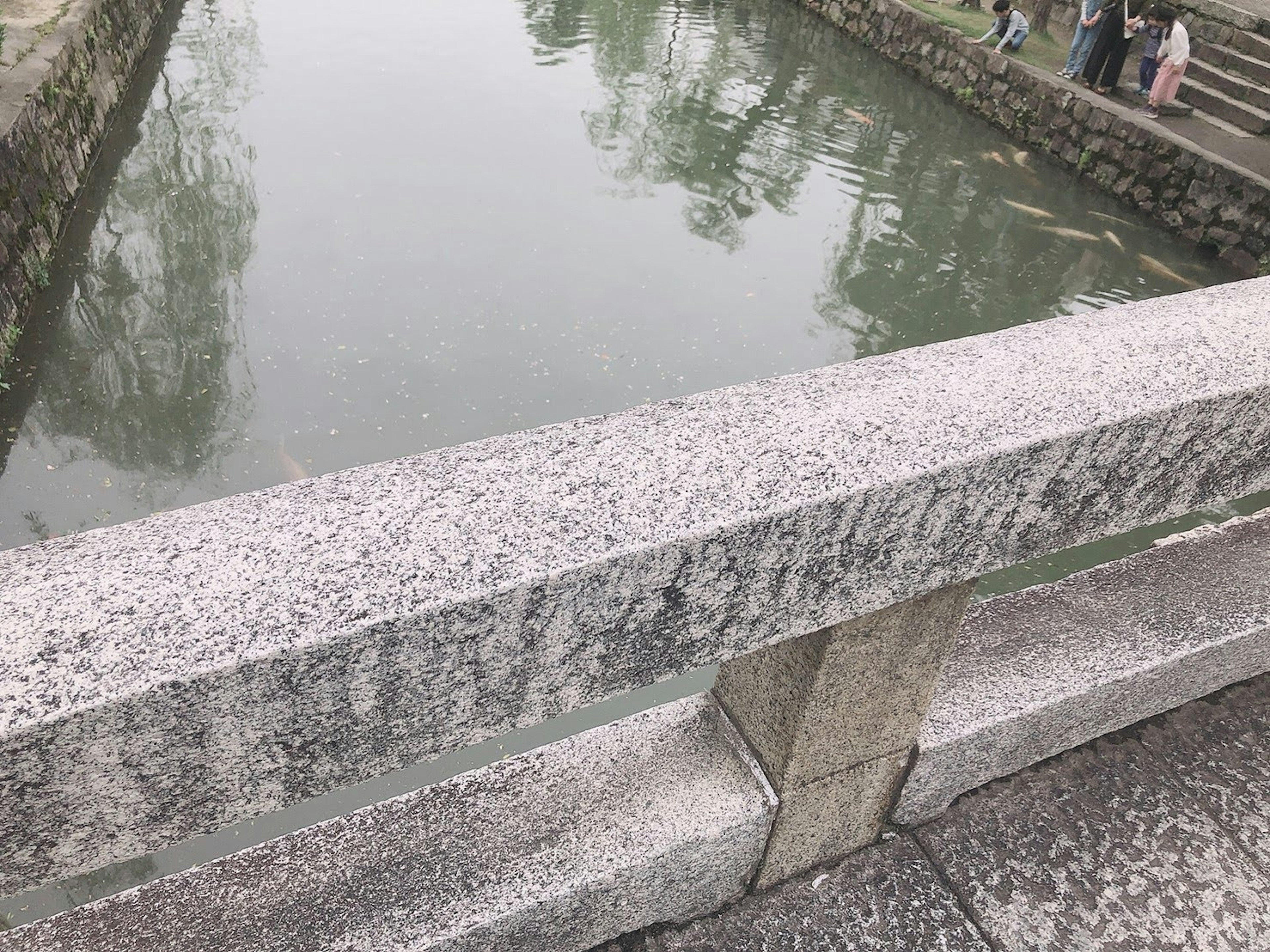 Barandilla de puente de piedra que da a una superficie de agua tranquila