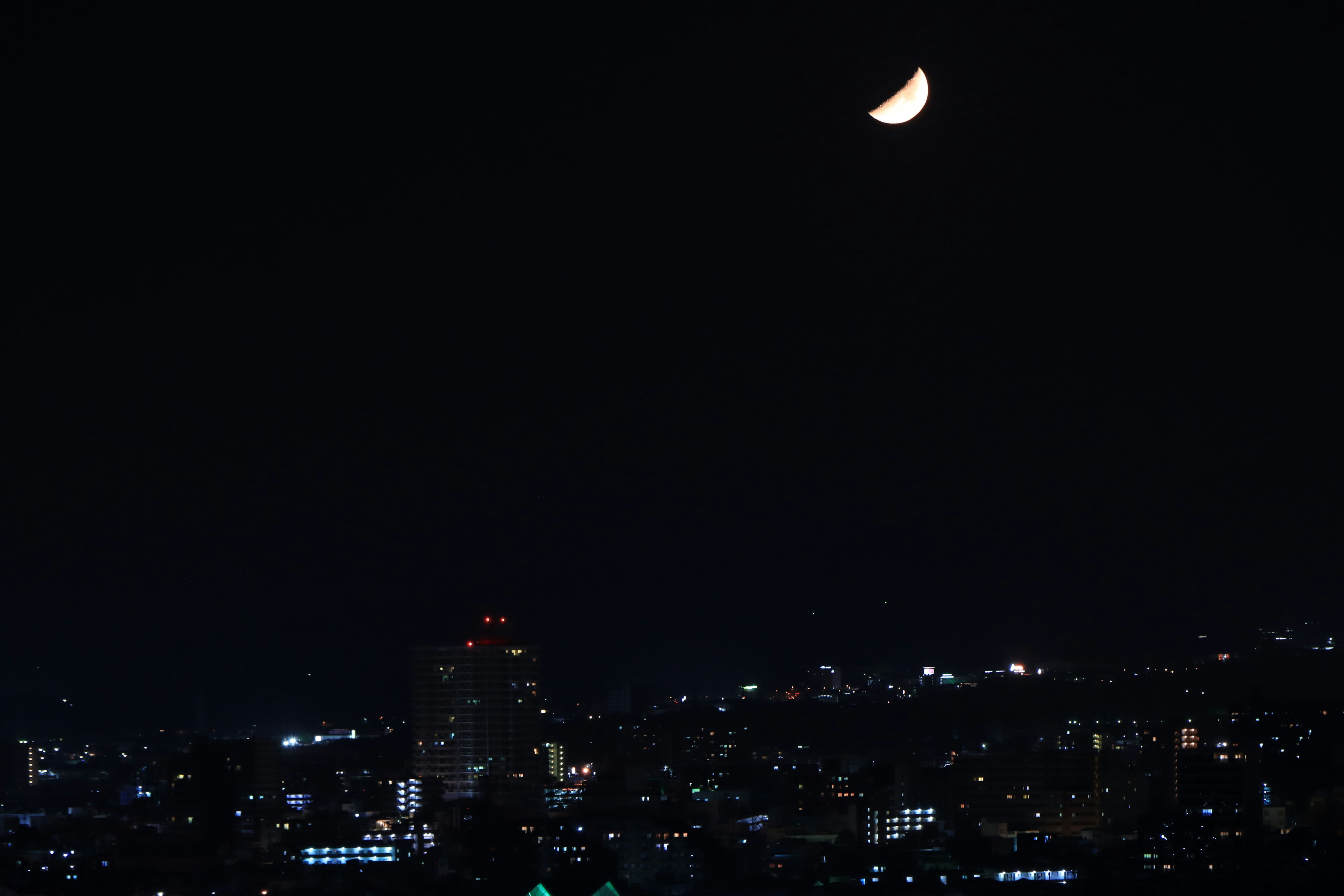 밤하늘의 초승달과 함께 빛나는 도시 경관