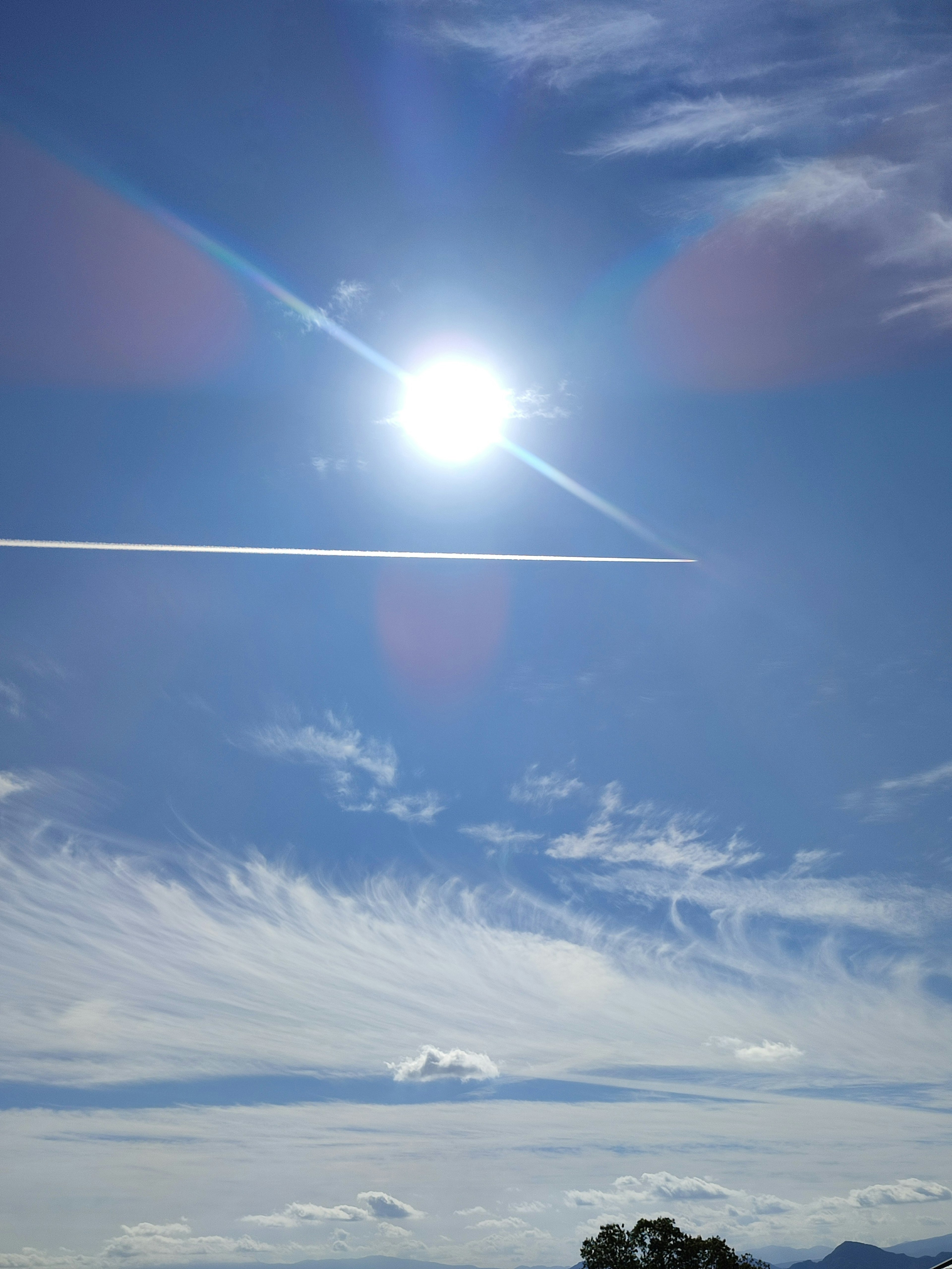 Sole luminoso in un cielo blu chiaro con scia di aeroplano