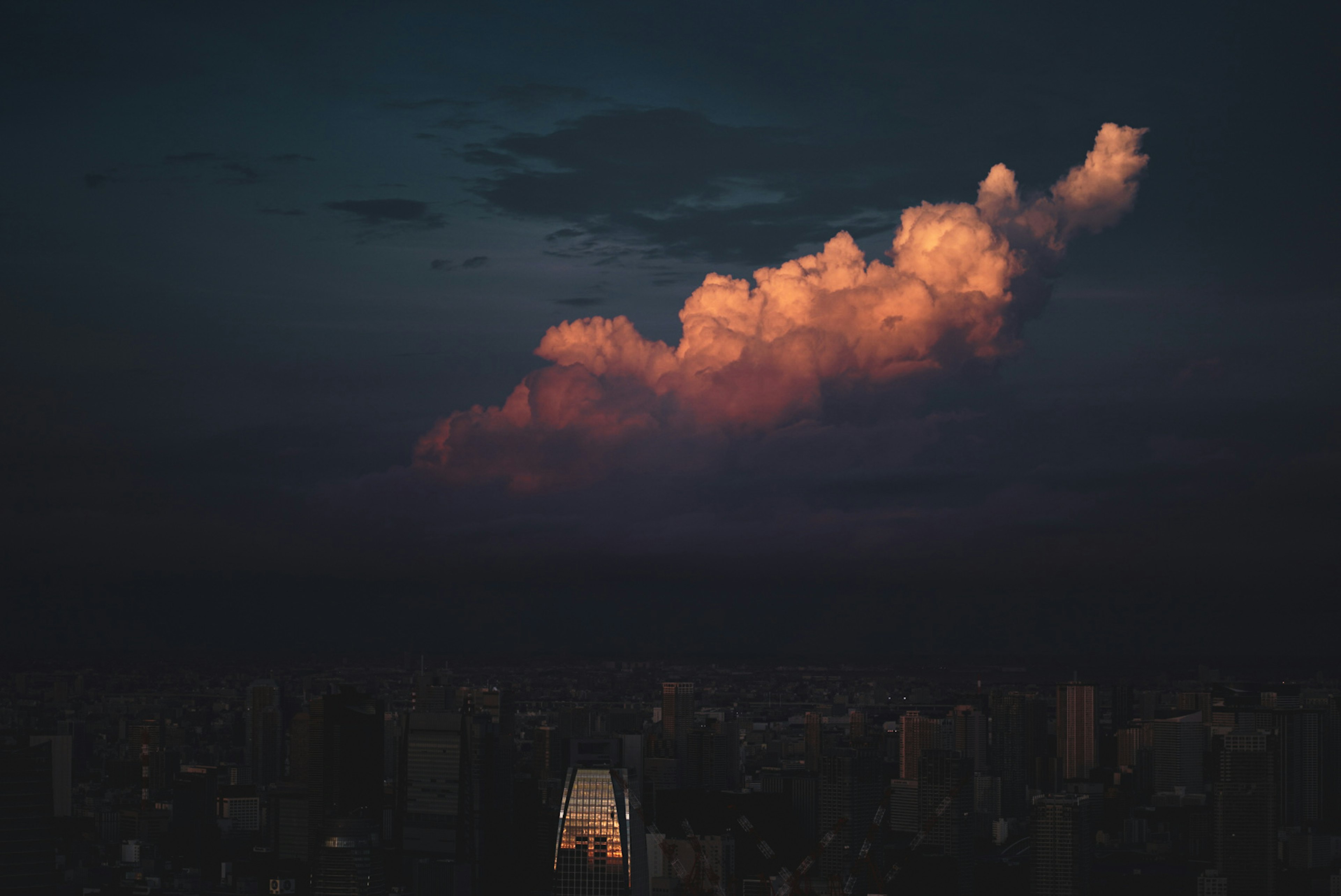 暗い空に浮かぶオレンジ色の雲と都市のシルエット