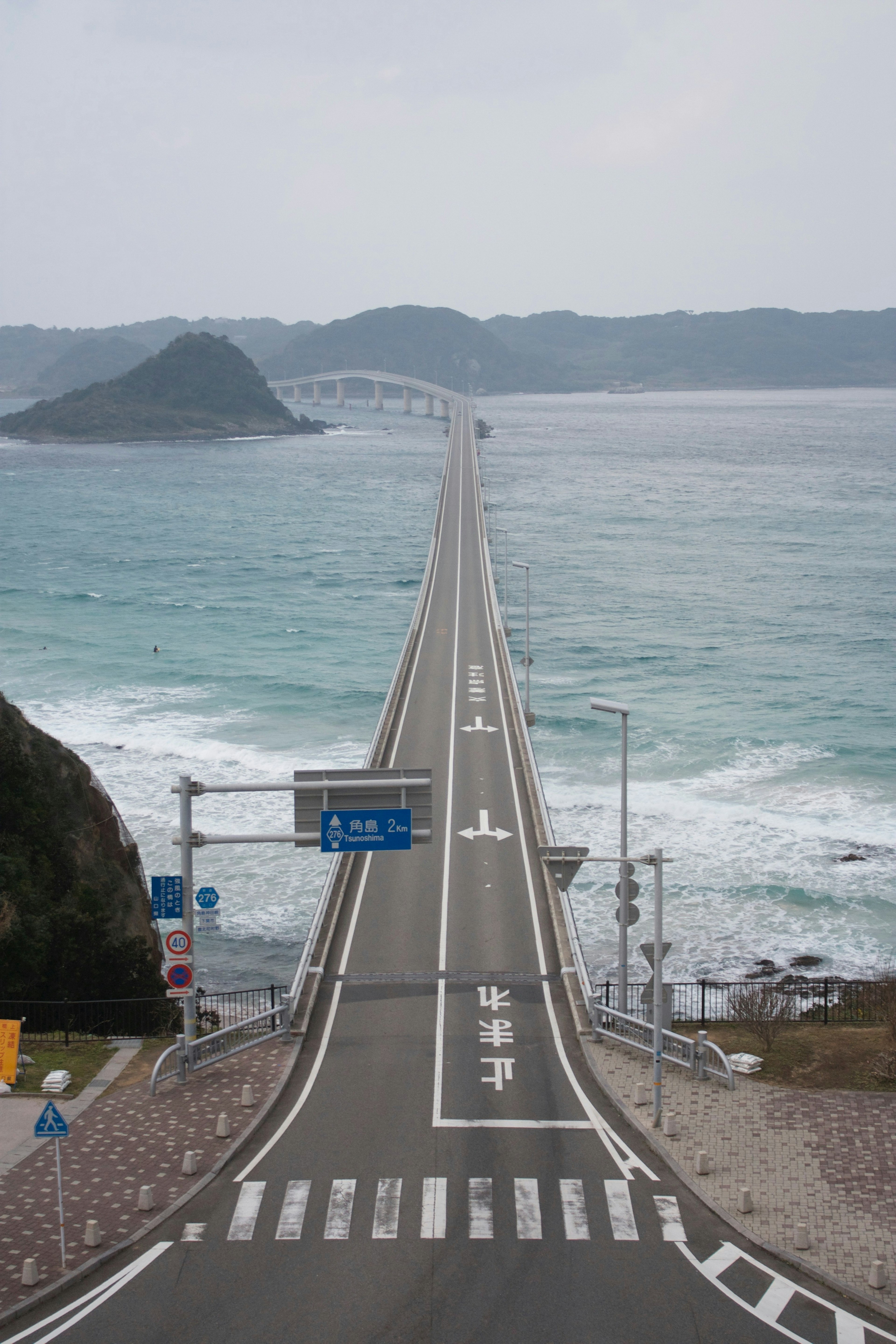 Long bridge extending over the sea with visible island and waves