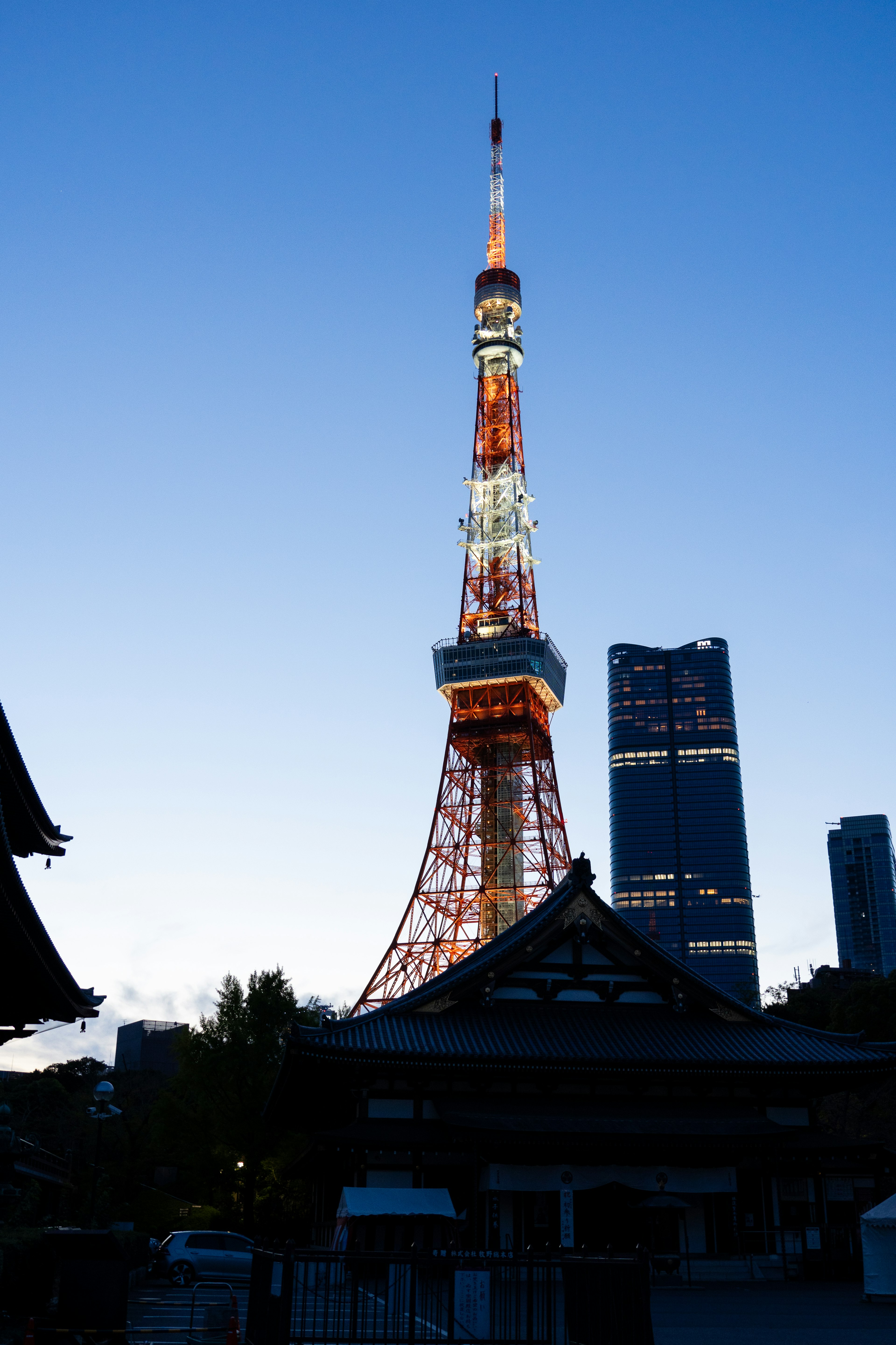 Tokyo Tower illuminated at dusk with modern buildings in the background