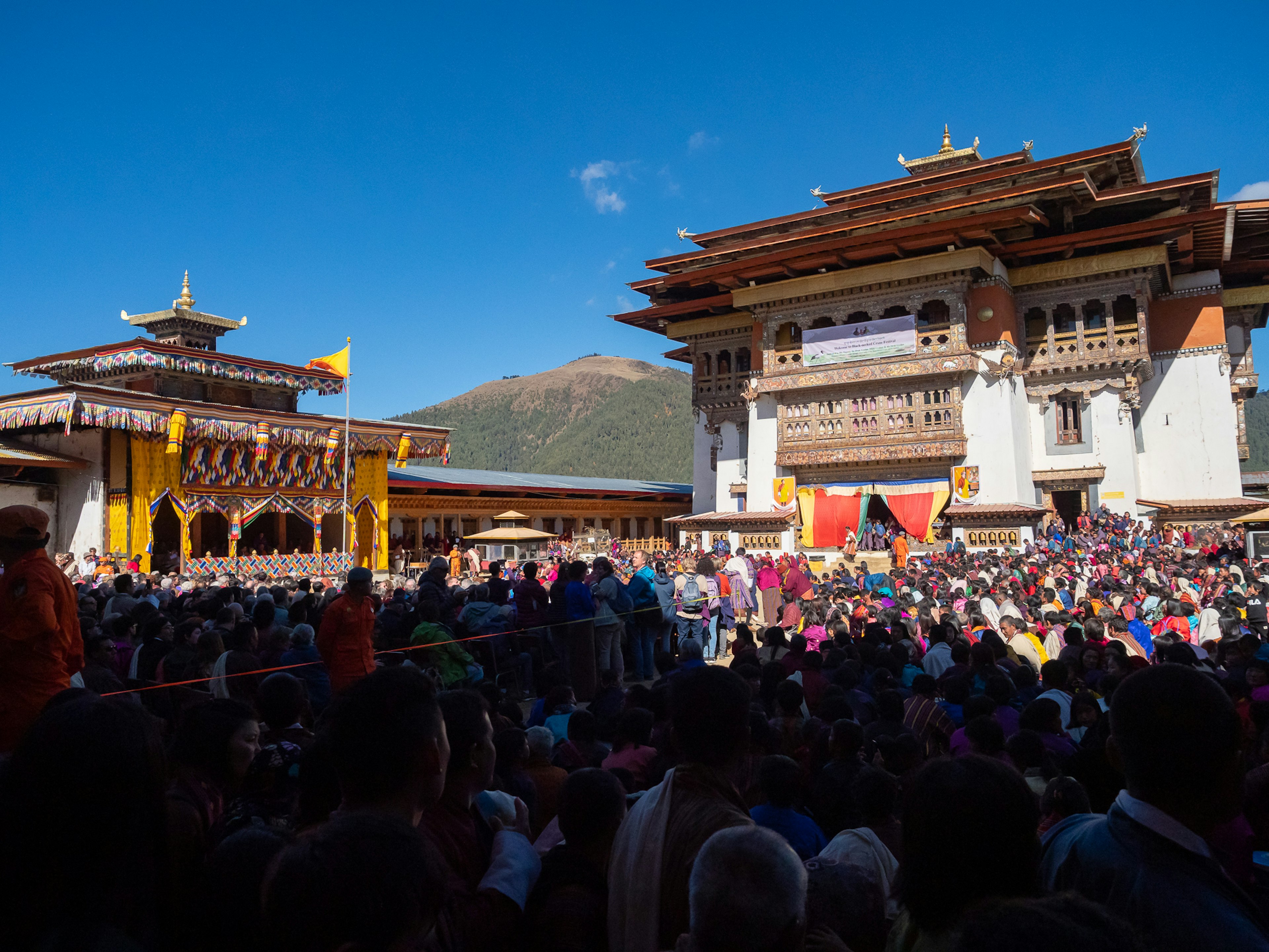 Crowd gathered for a festival in Bhutan with grand architecture