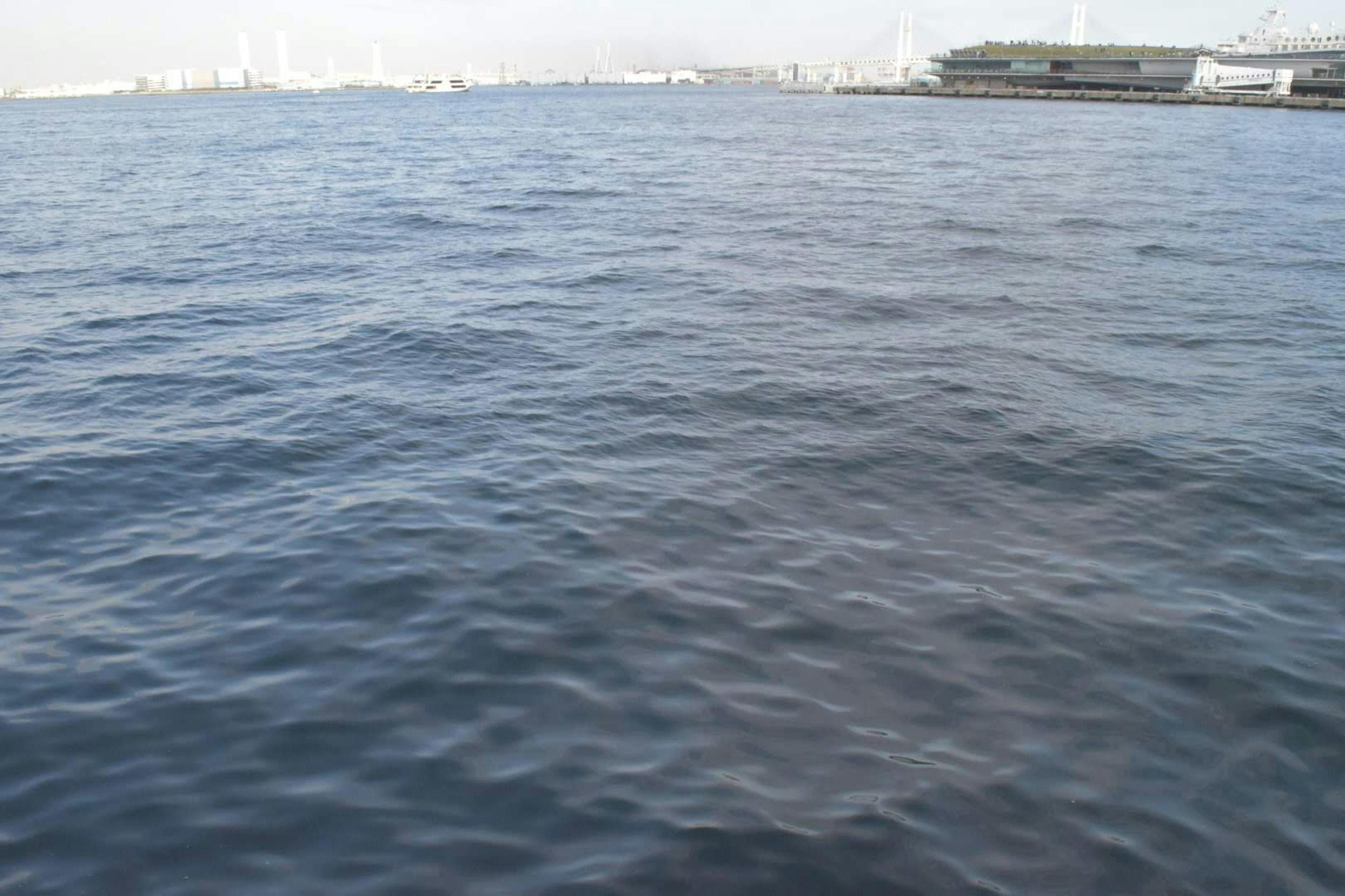 Superficie del mar tranquila con barcos a la distancia