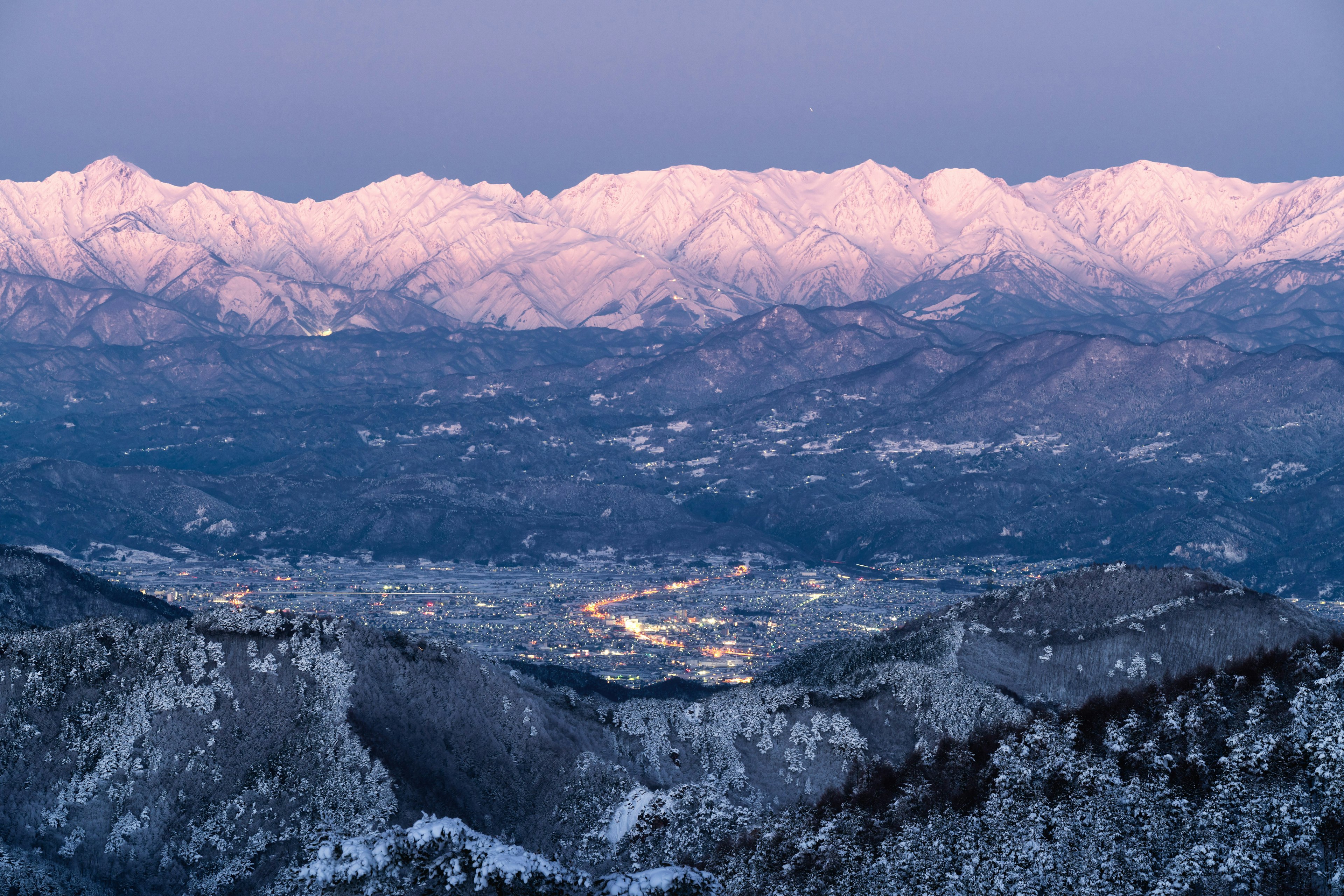 雪に覆われた山々と薄明かりの町の美しい風景