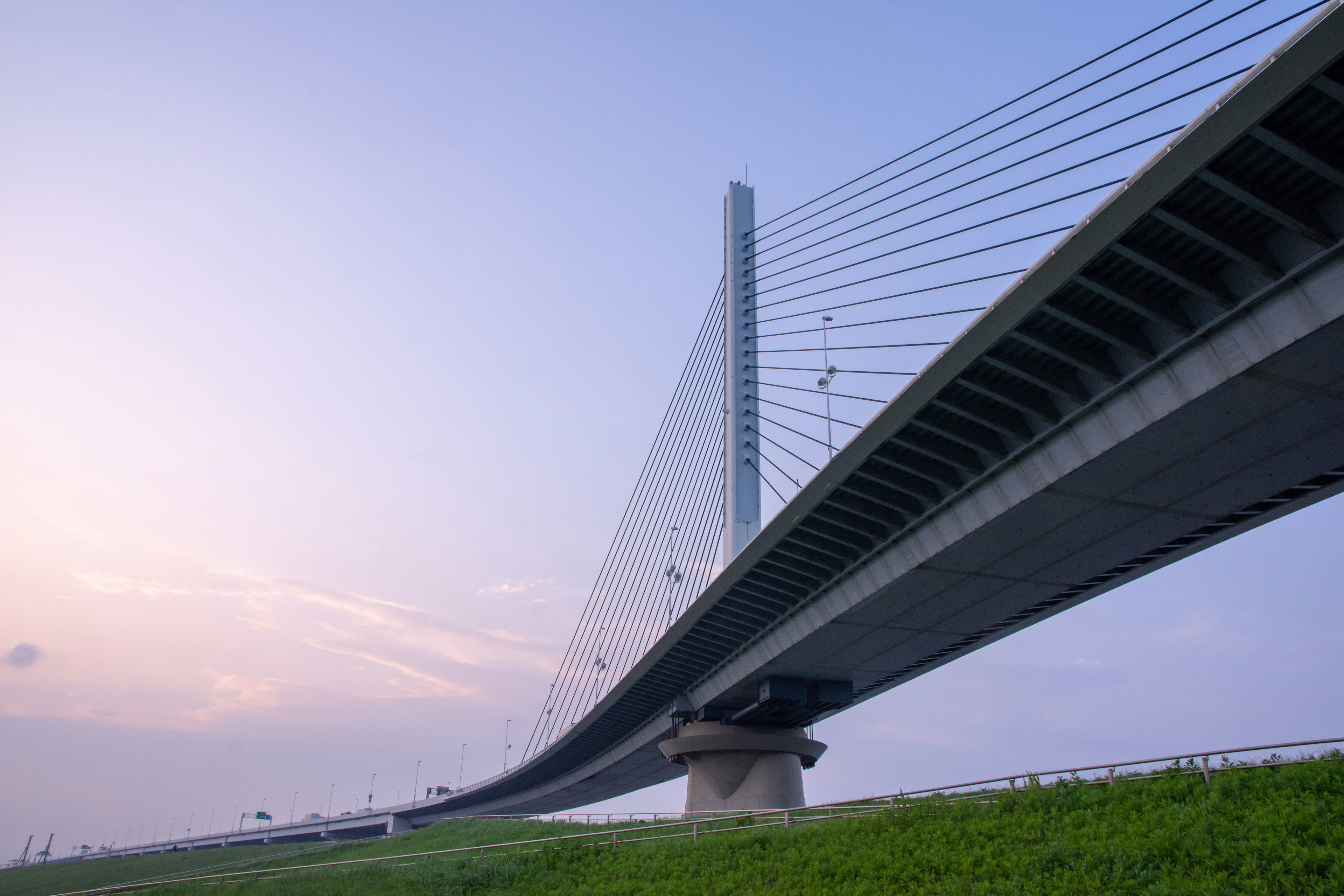 Eine beeindruckende Schrägseilbrücke, die sich gegen einen Sonnenuntergangshimmel erhebt