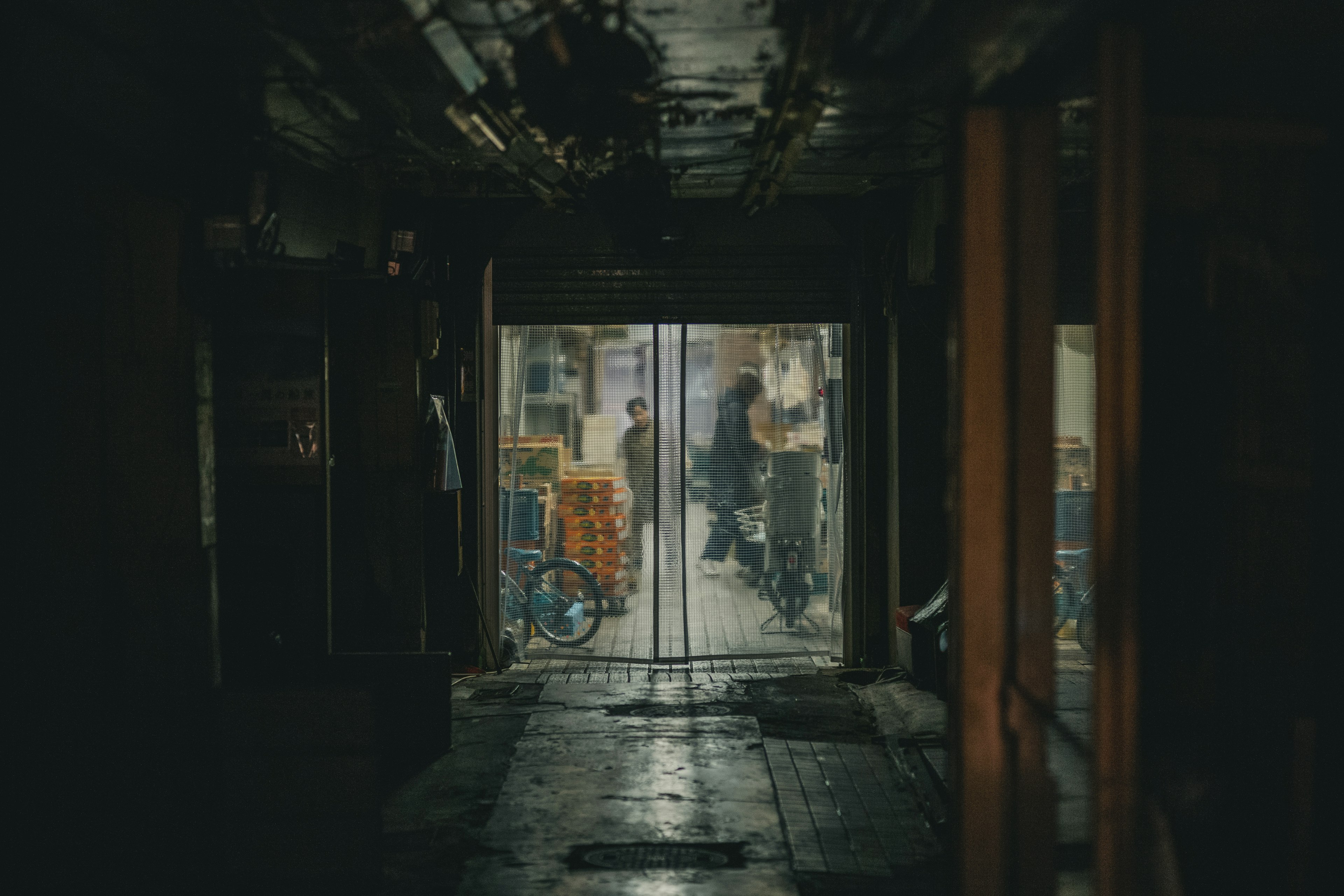 Lorong redup yang mengarah ke toko terang dengan orang-orang di dalamnya