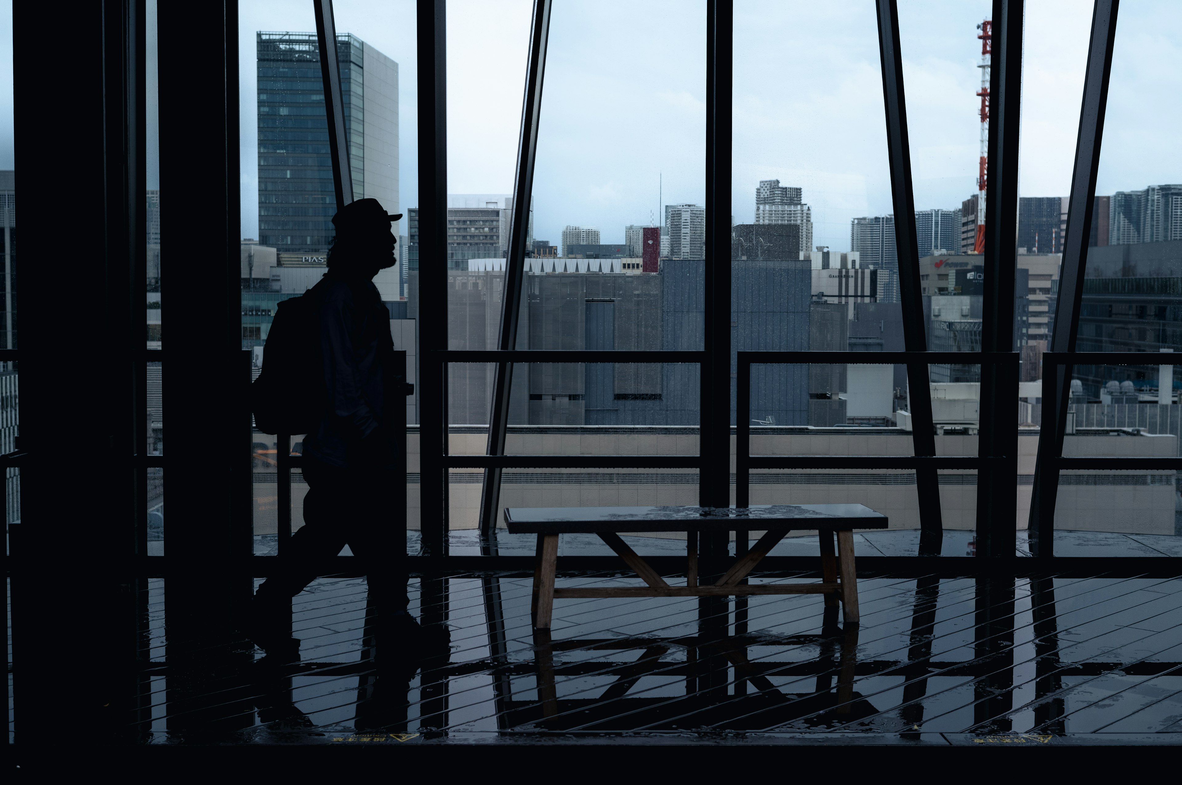 Silhouette of a person walking near large windows overlooking a city