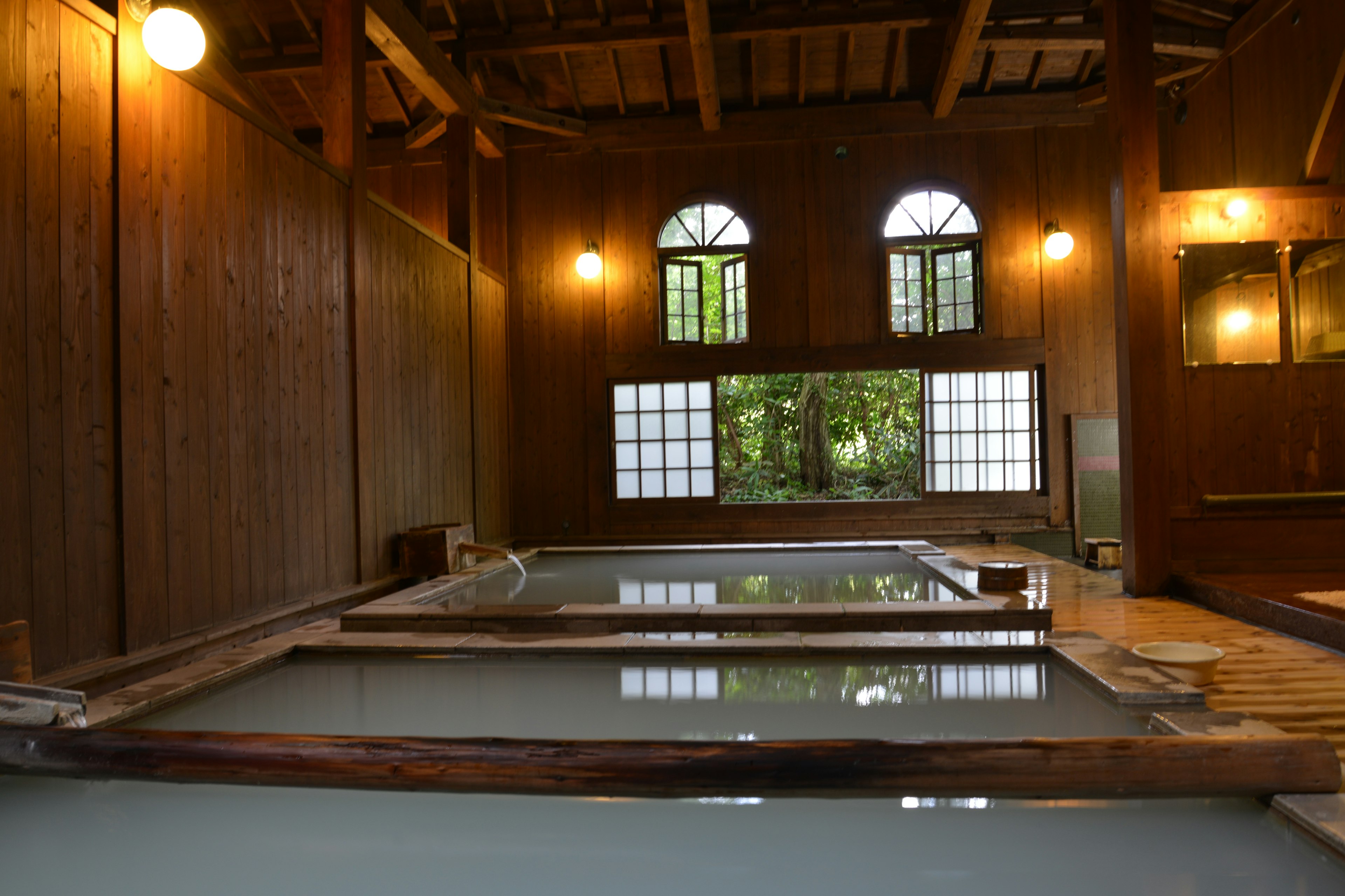 Interior de una instalación onsen de madera con grandes ventanas