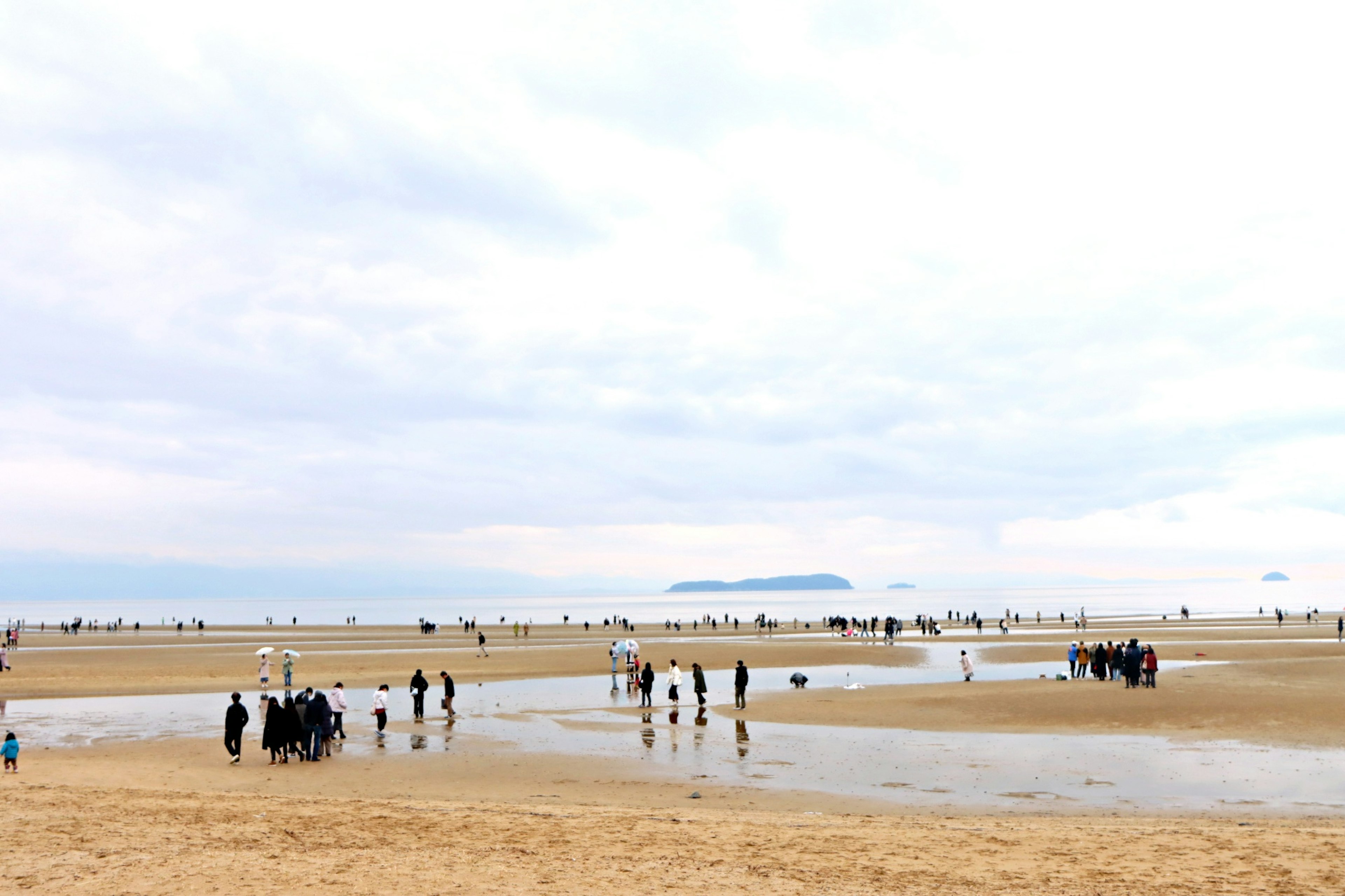 Strandlandschaft mit Menschen und bewölkem Himmel