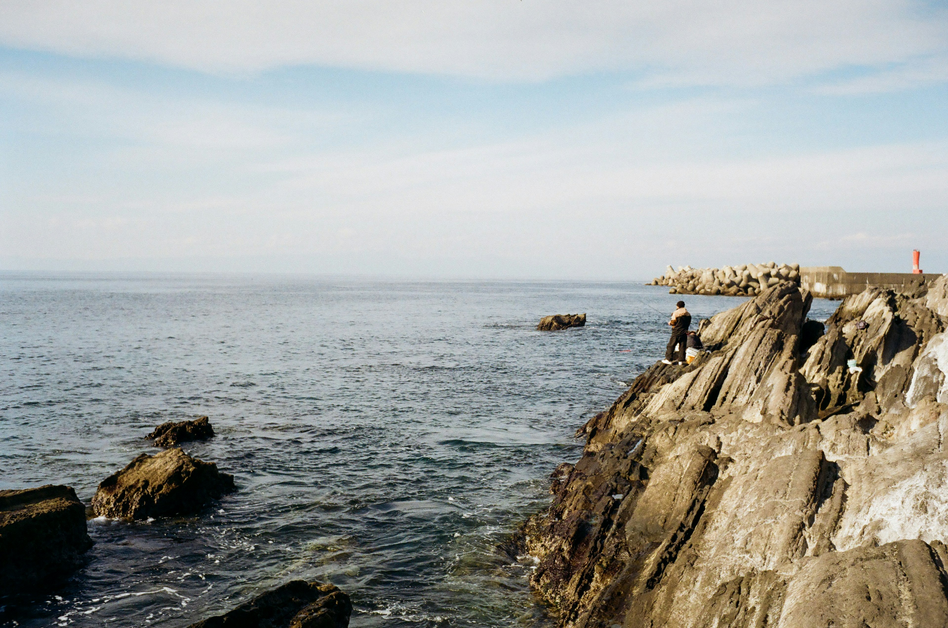 Une personne debout sur une côte rocheuse avec une vue sur la mer calme