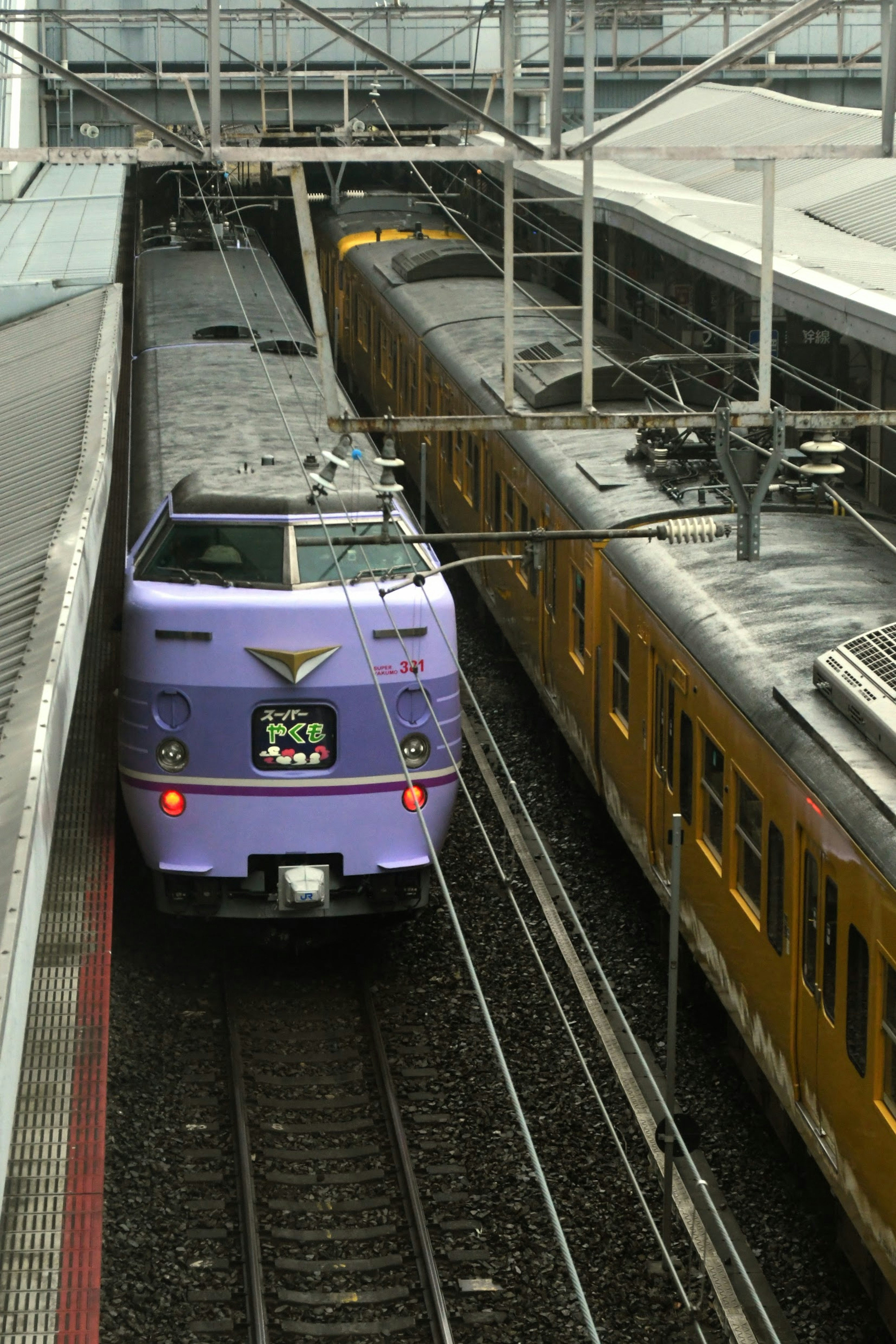 Treno espresso viola in stazione con un altro treno vicino