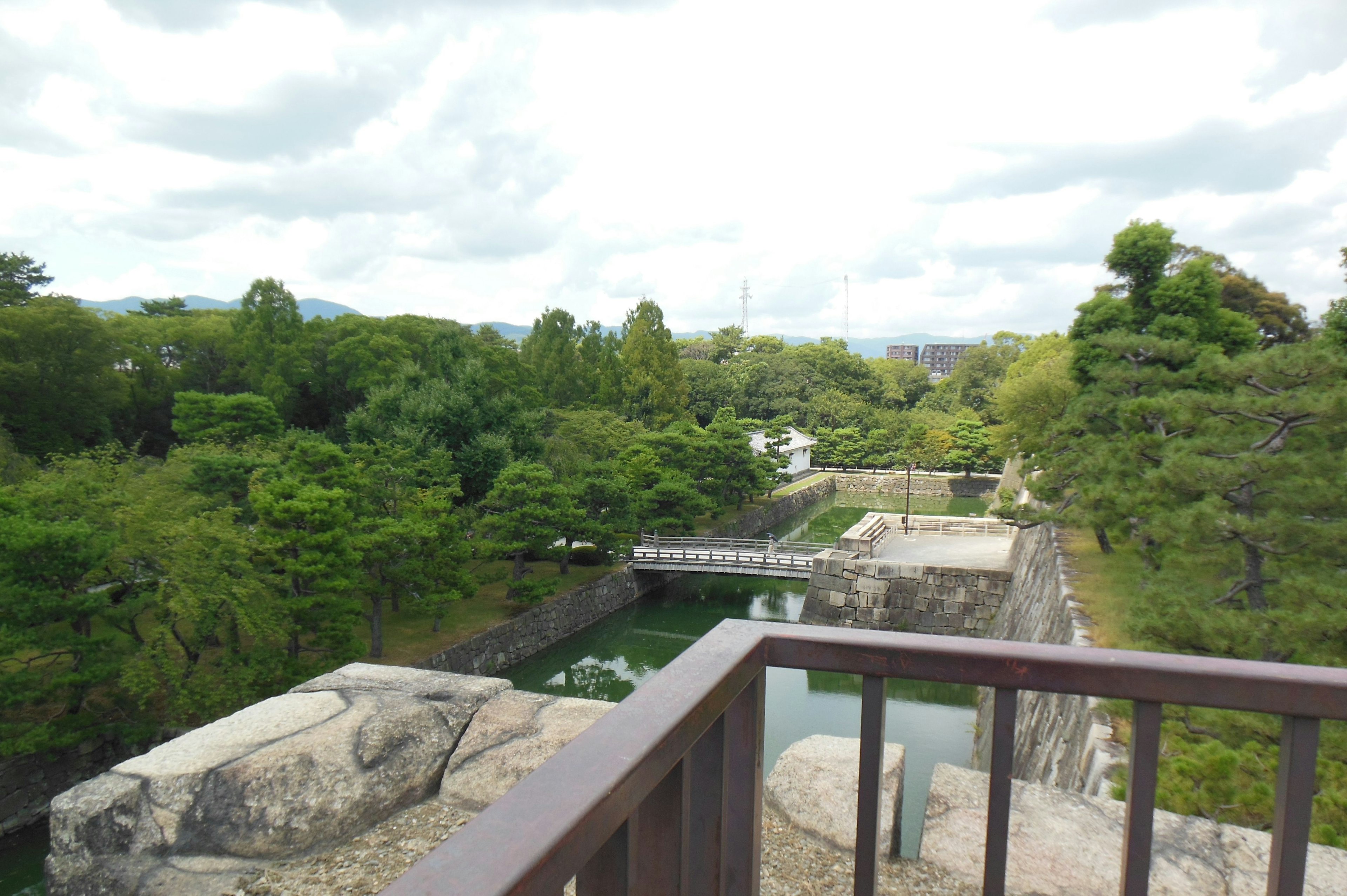 Vista panoramica da un punto di osservazione del castello con vegetazione lussureggiante e un ponte