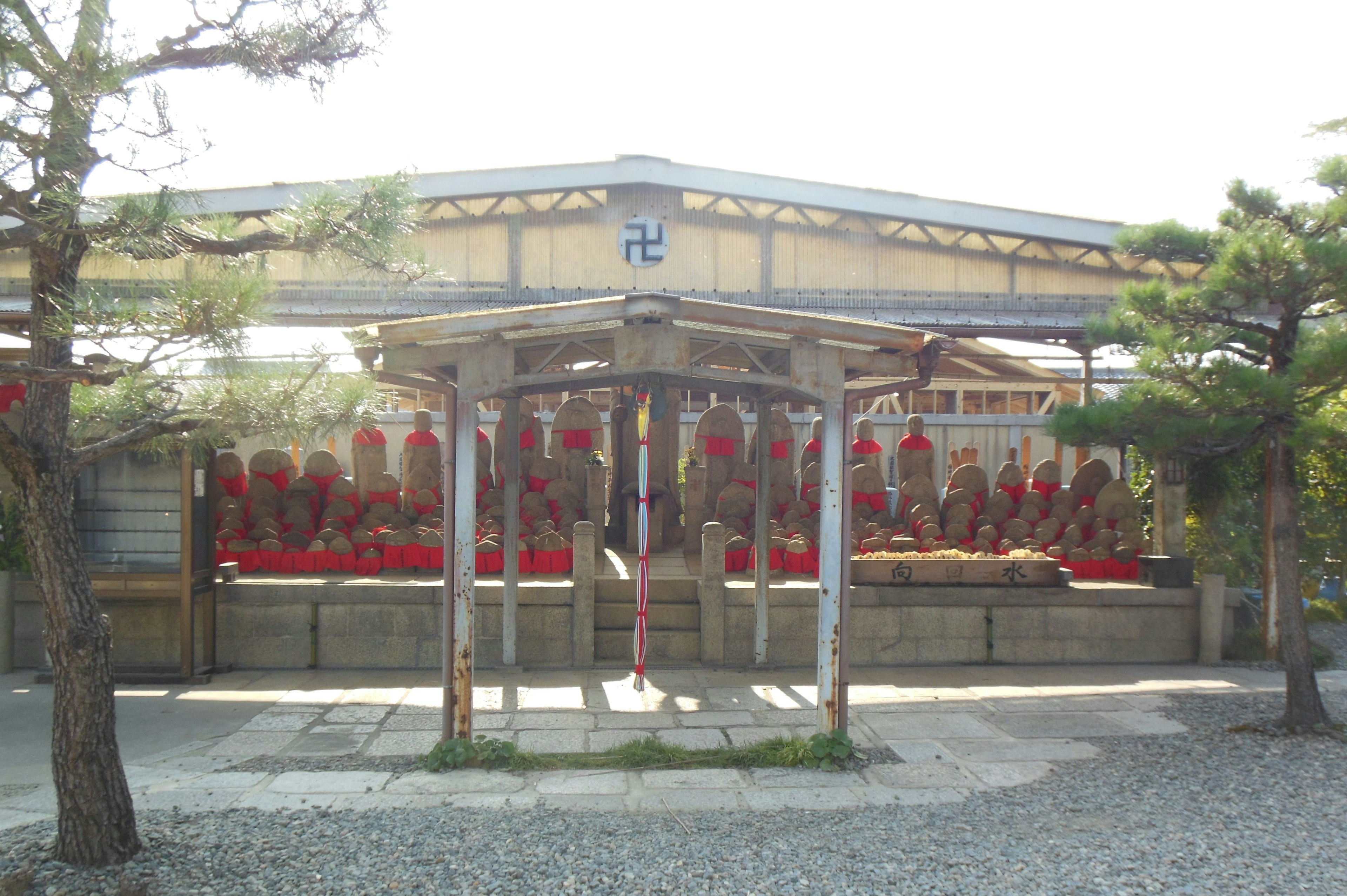 A shrine with red decorations in the foreground and surrounding trees