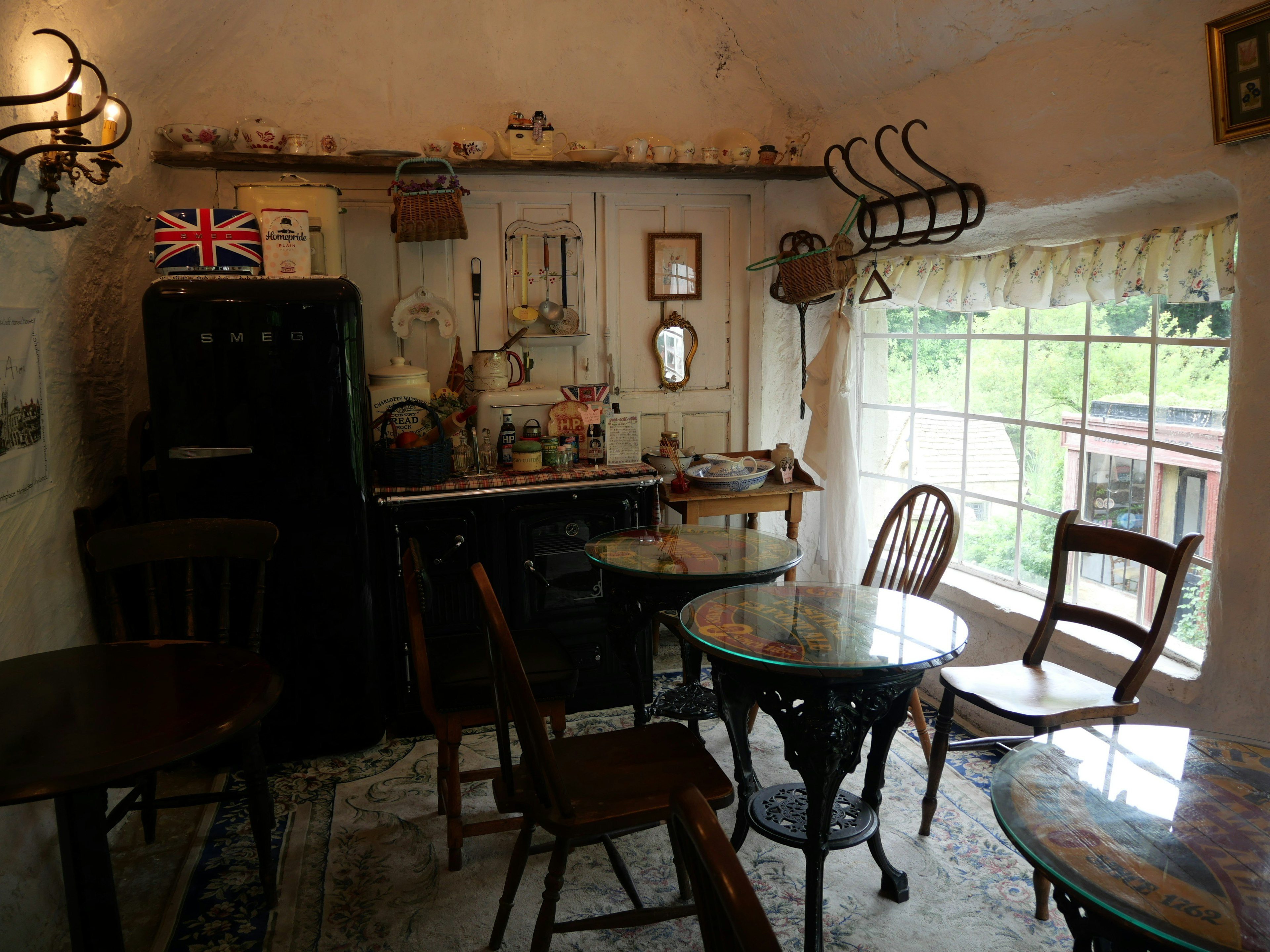 Interior de una cafetería acogedora con muebles vintage y una pared decorada con una bandera británica