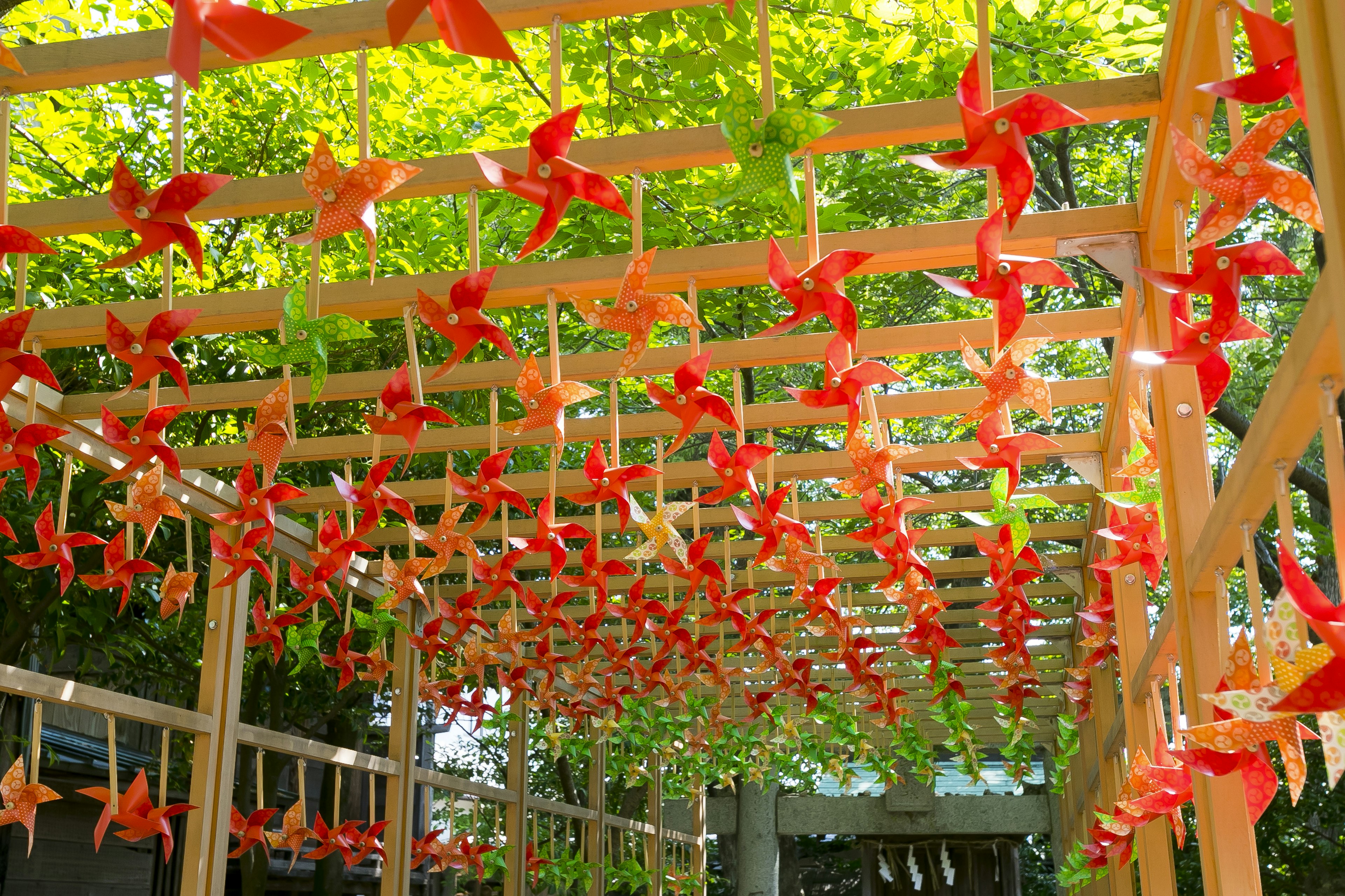 Pergola kayu yang indah dihiasi dengan kincir angin merah yang tergantung