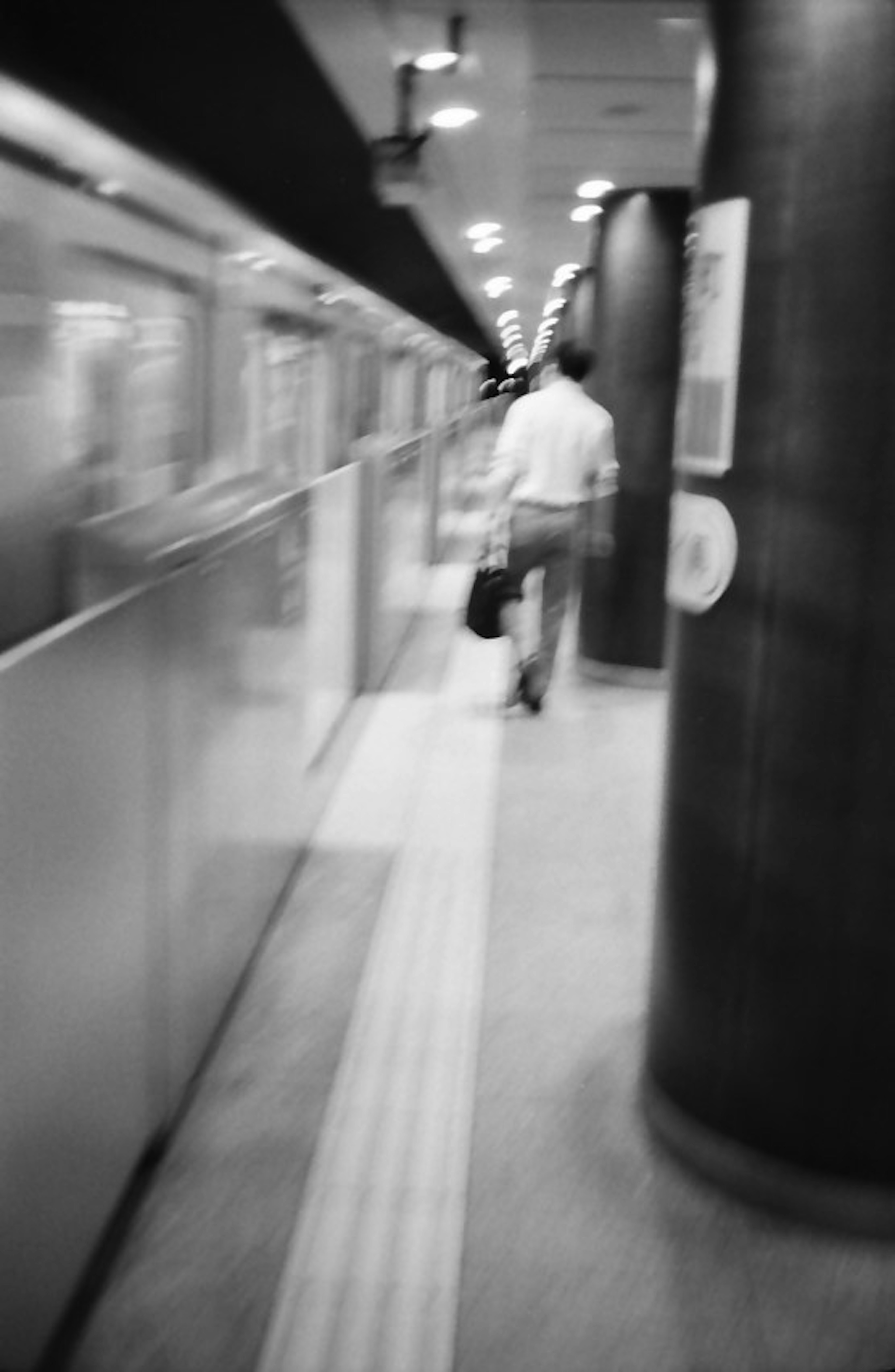 Un'immagine sfocata in bianco e nero di una persona che cammina in una stazione della metropolitana