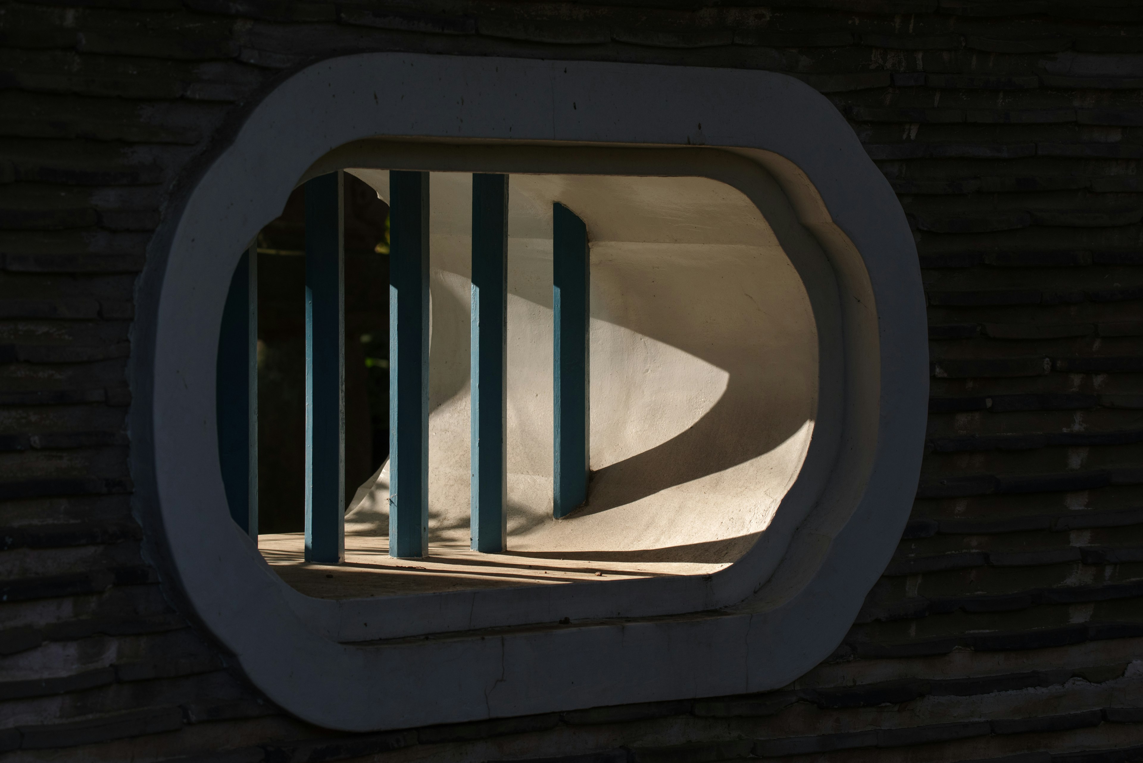 Vista a través de una ventana ovalada que muestra columnas azules y paredes curvas