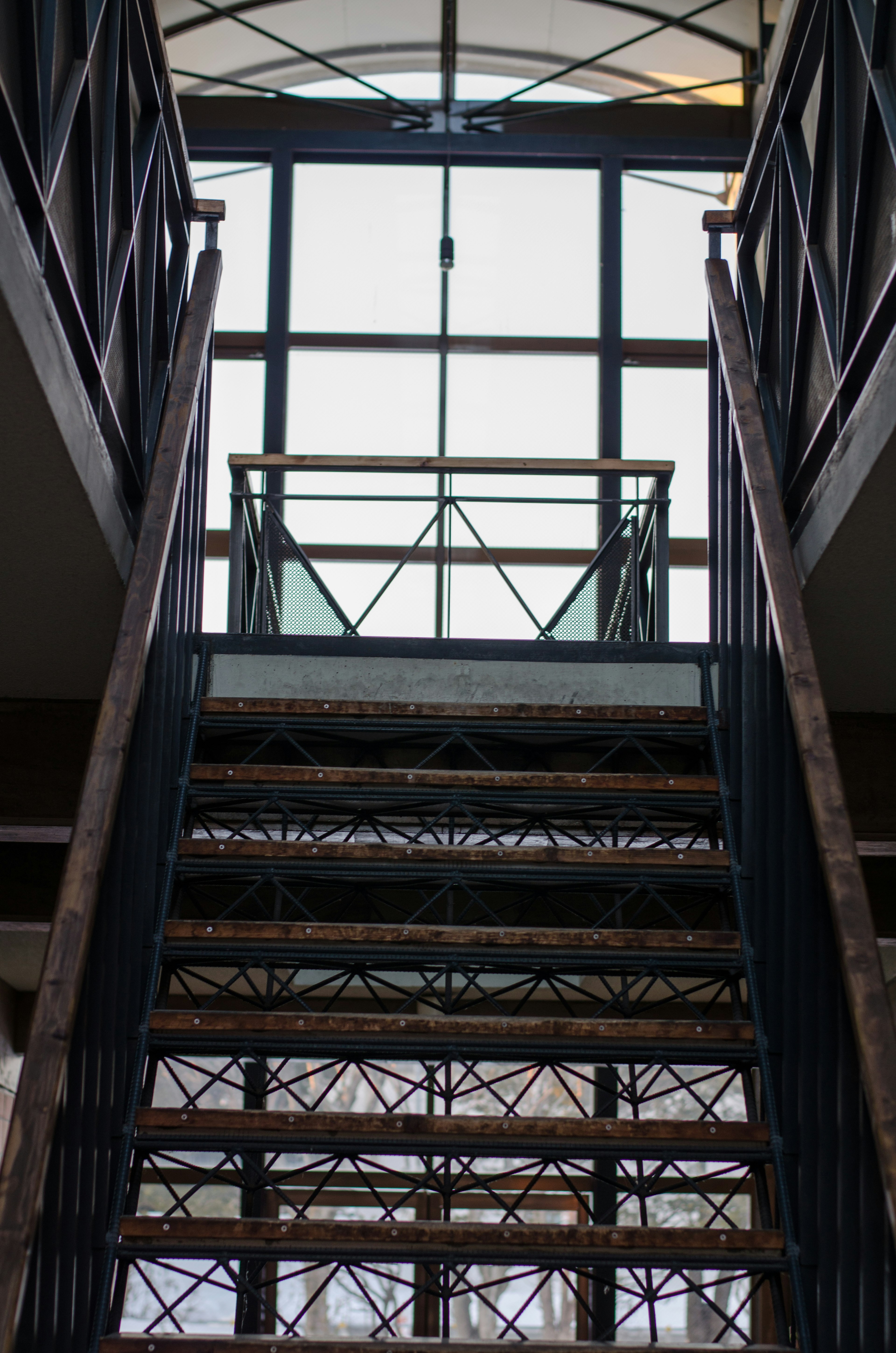 Blick von unten auf eine Treppe, die zu einem großen Fenster in einem modernen Gebäude führt