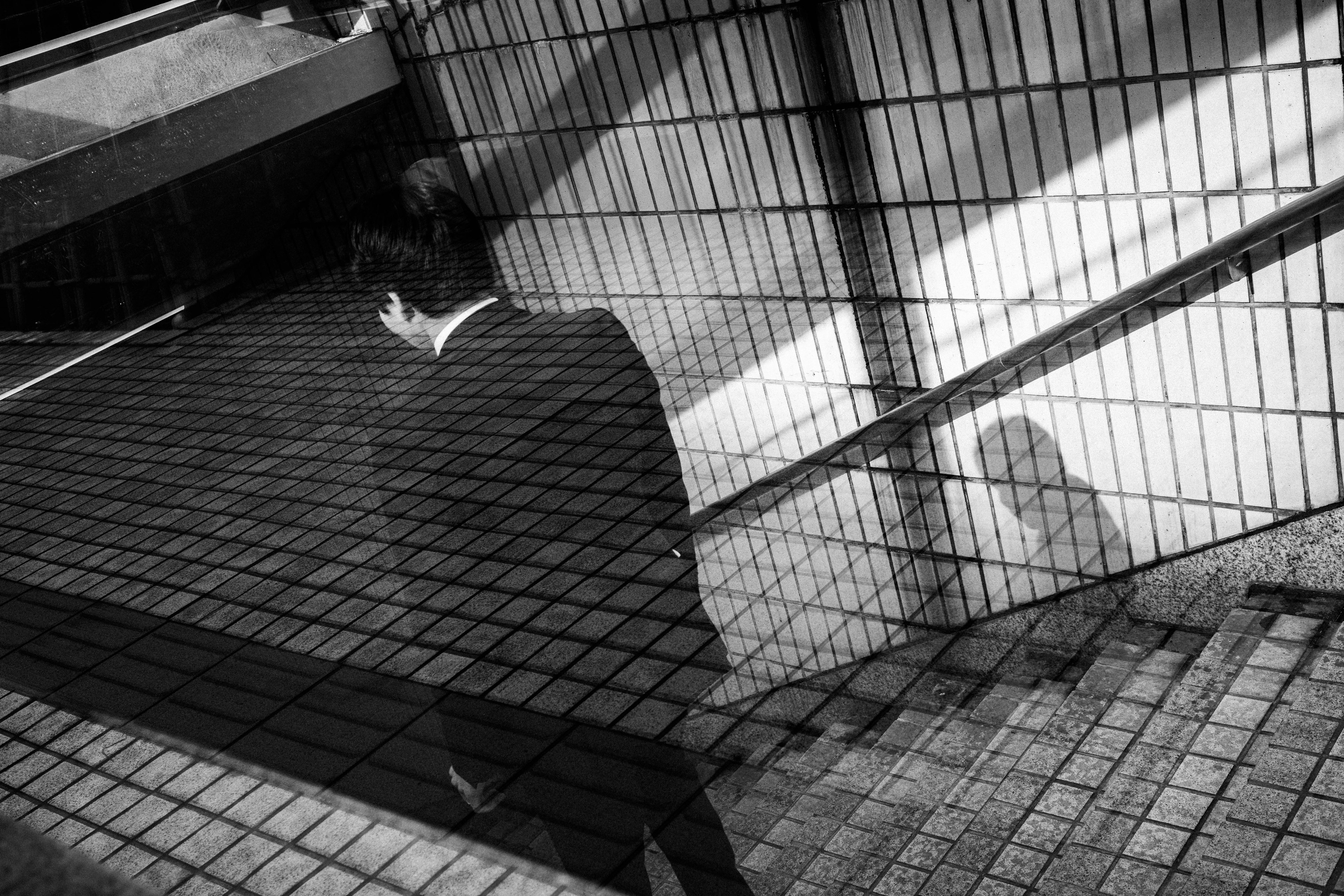 Man in a suit walking down stairs with a shadowy figure