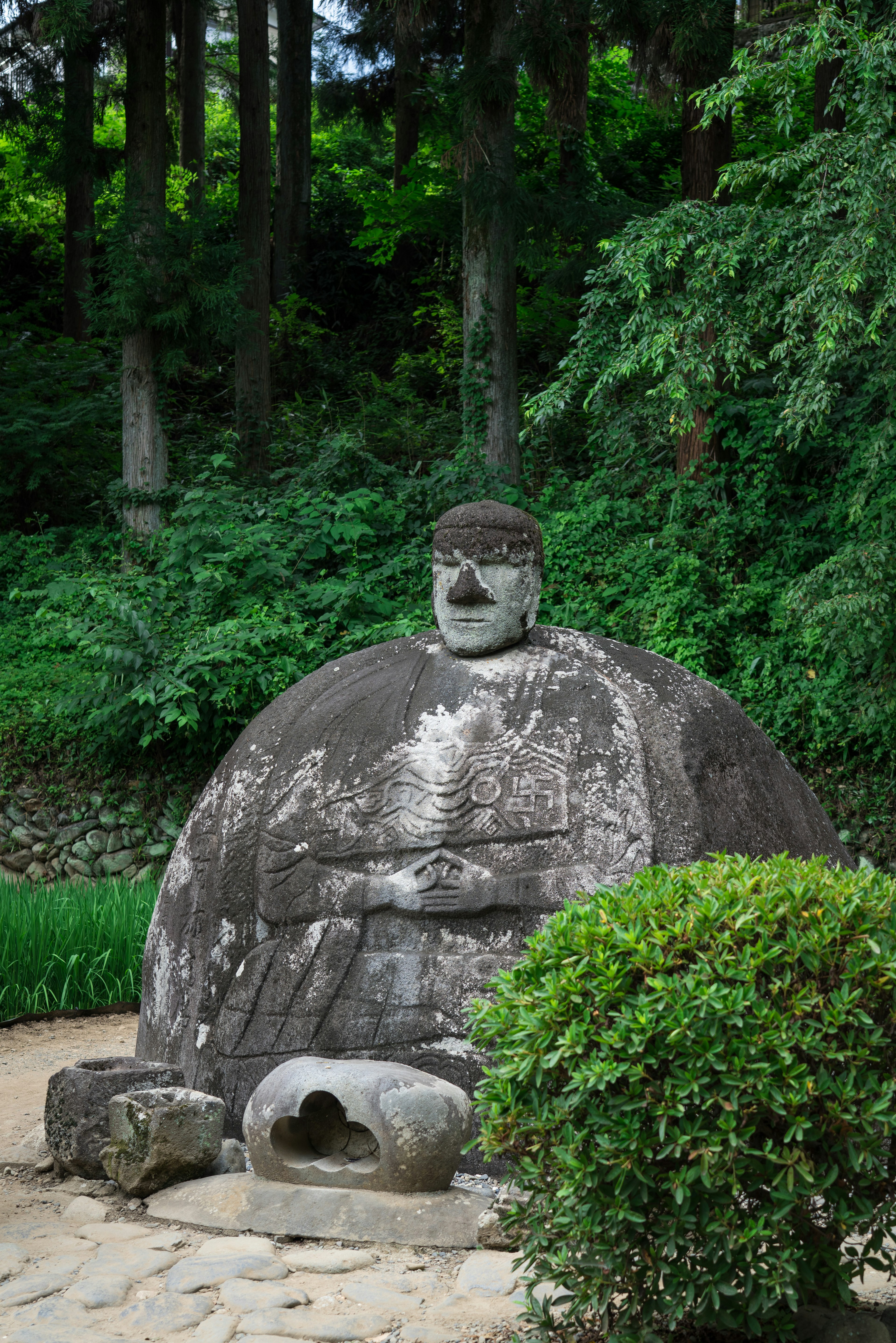 Stone statue of a Buddha surrounded by greenery