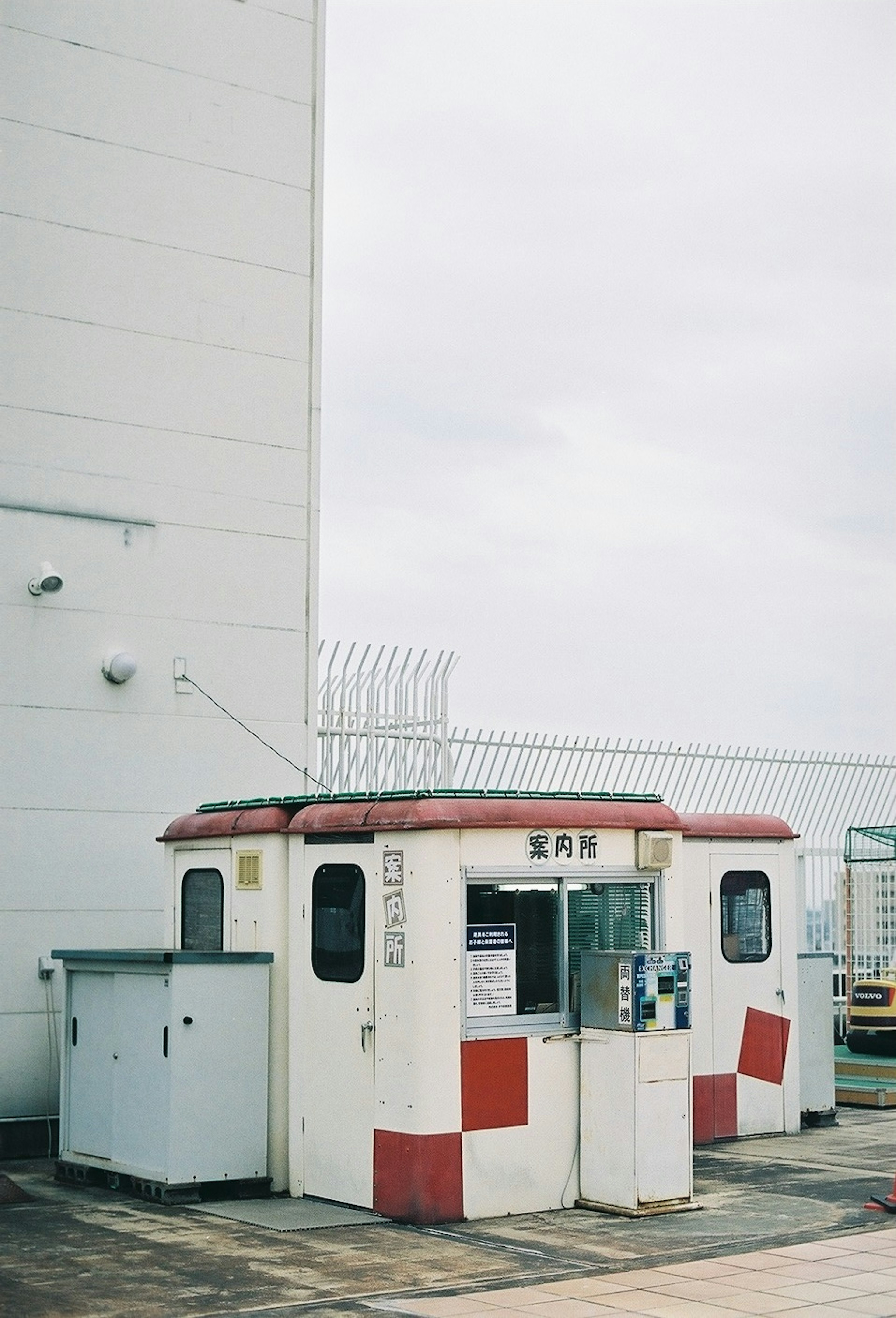 Un poste de sécurité rouge et blanc situé à côté d'un grand bâtiment sous un ciel nuageux