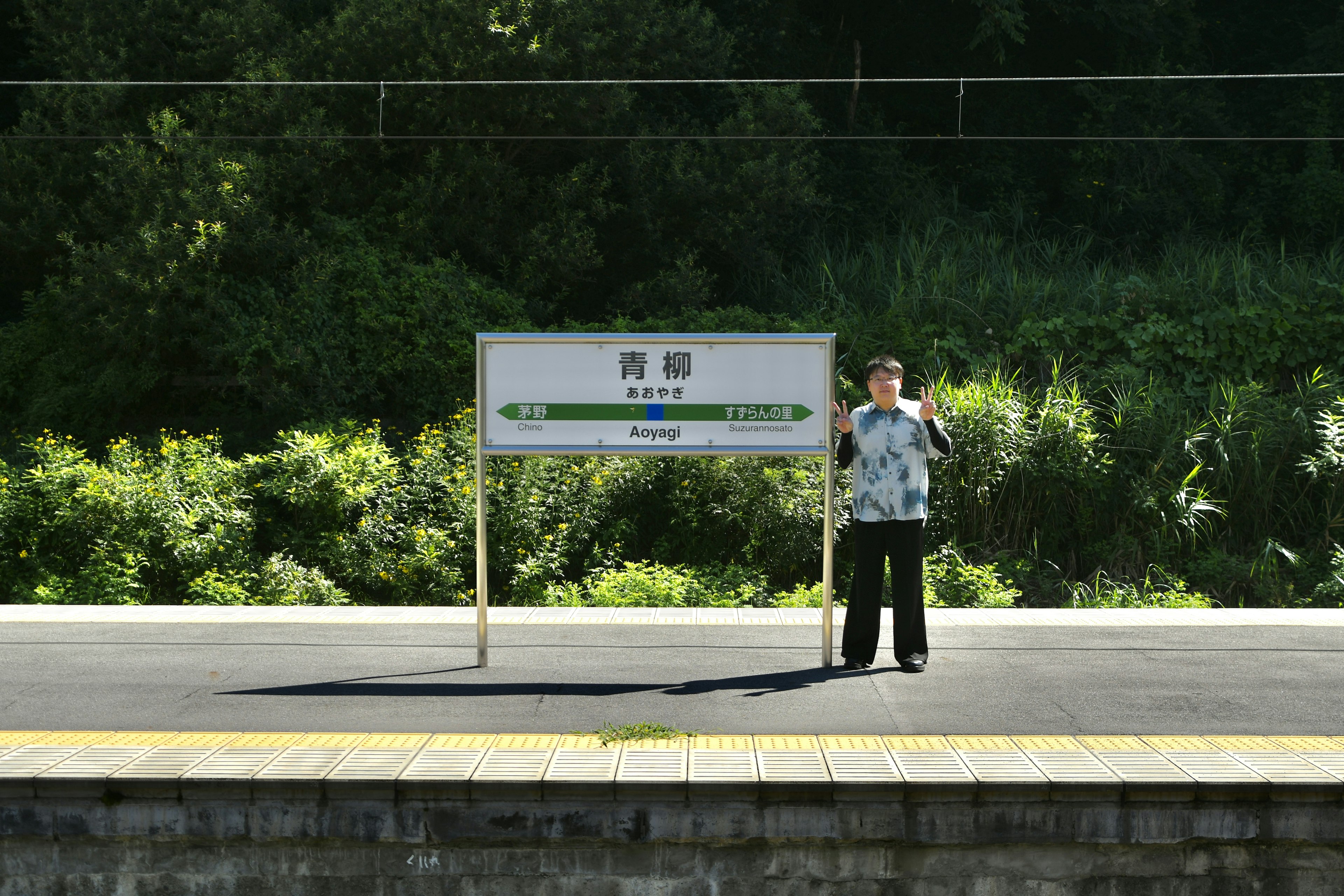 Person steht auf einem Bahnsteig neben einem Schild