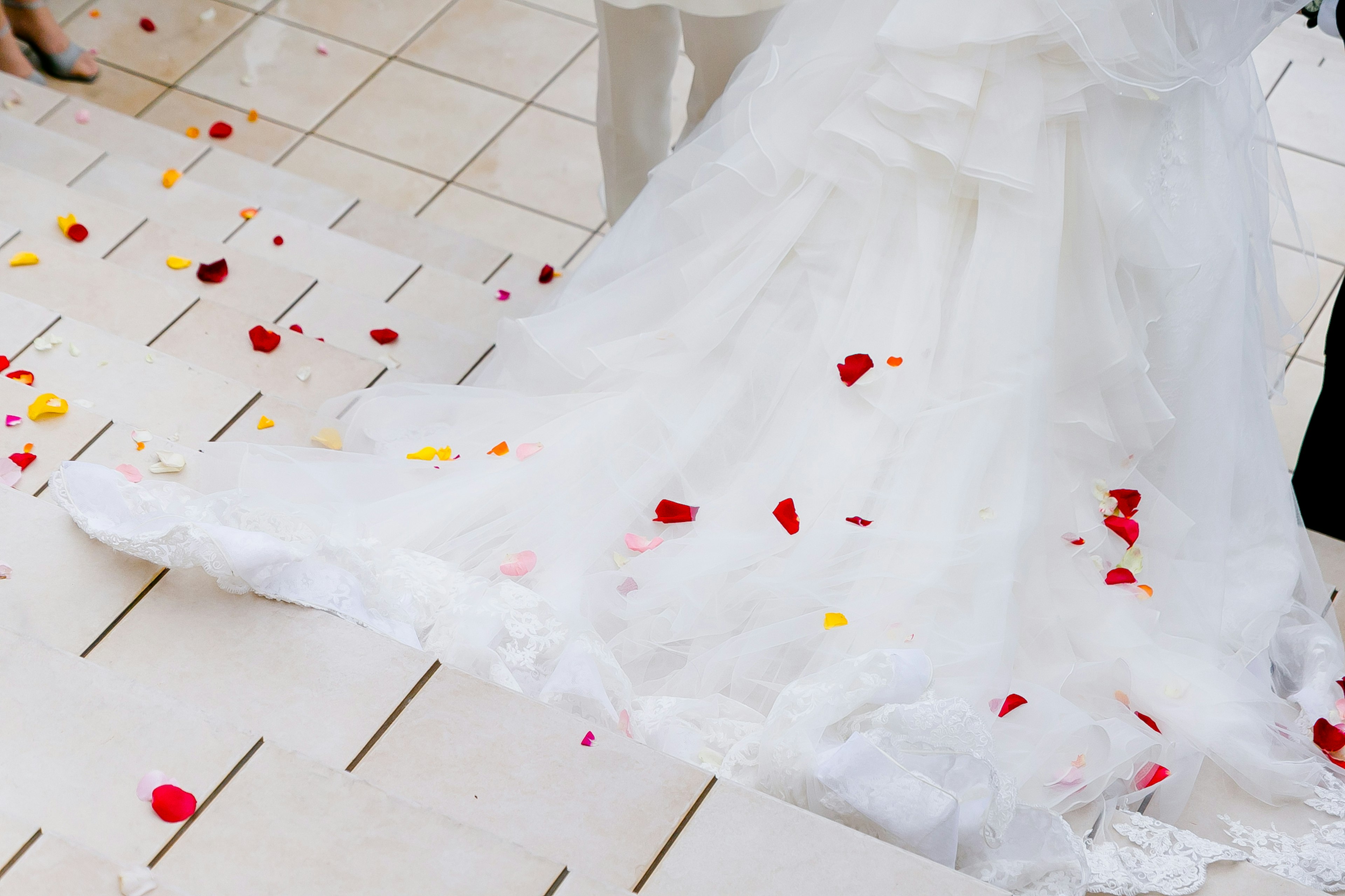 Scena di matrimonio con orlo di abito bianco e petali di fiori sparsi