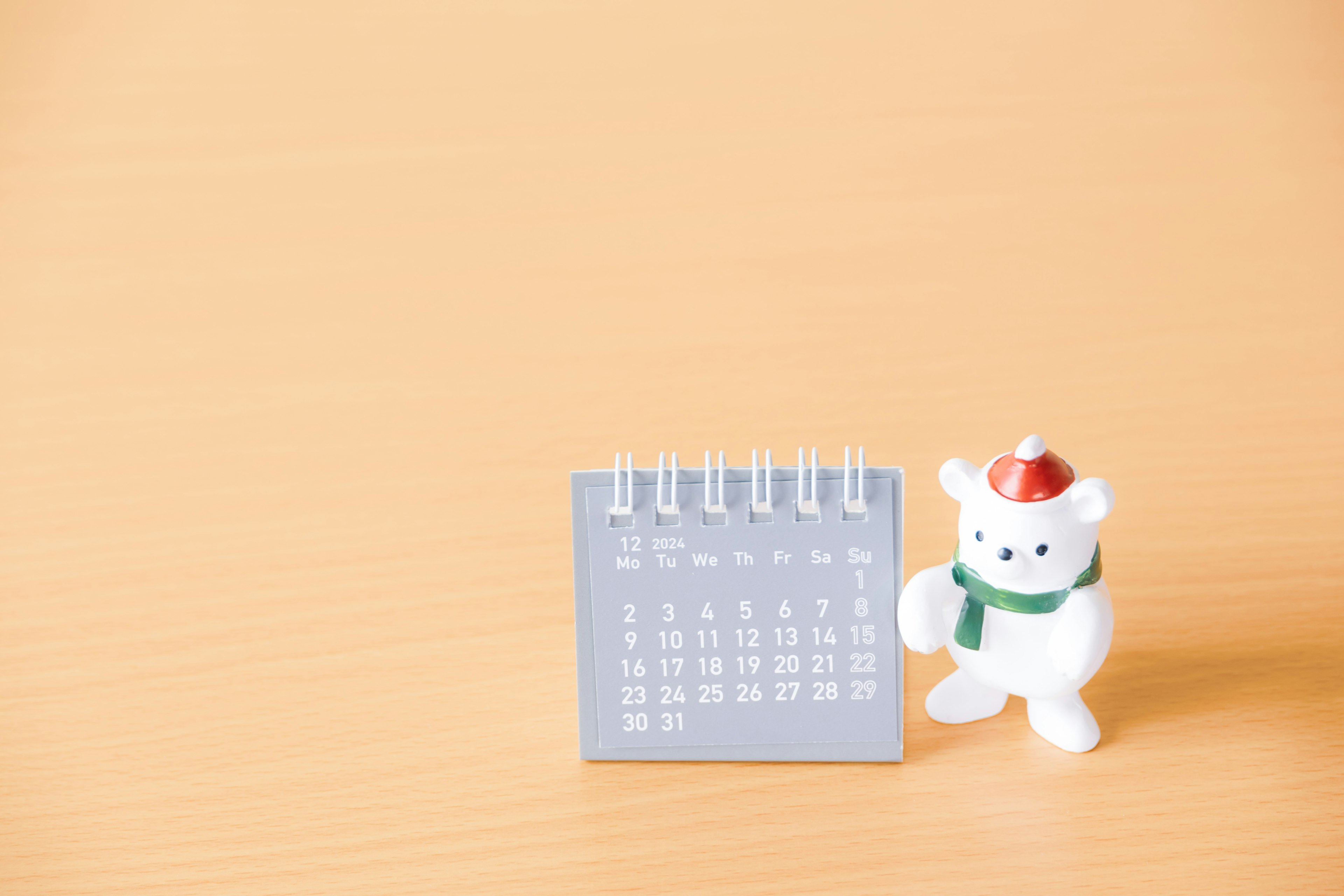 Ein kleiner Kalender neben einer weißen Bärenfigur mit einem Weihnachtsmannhut