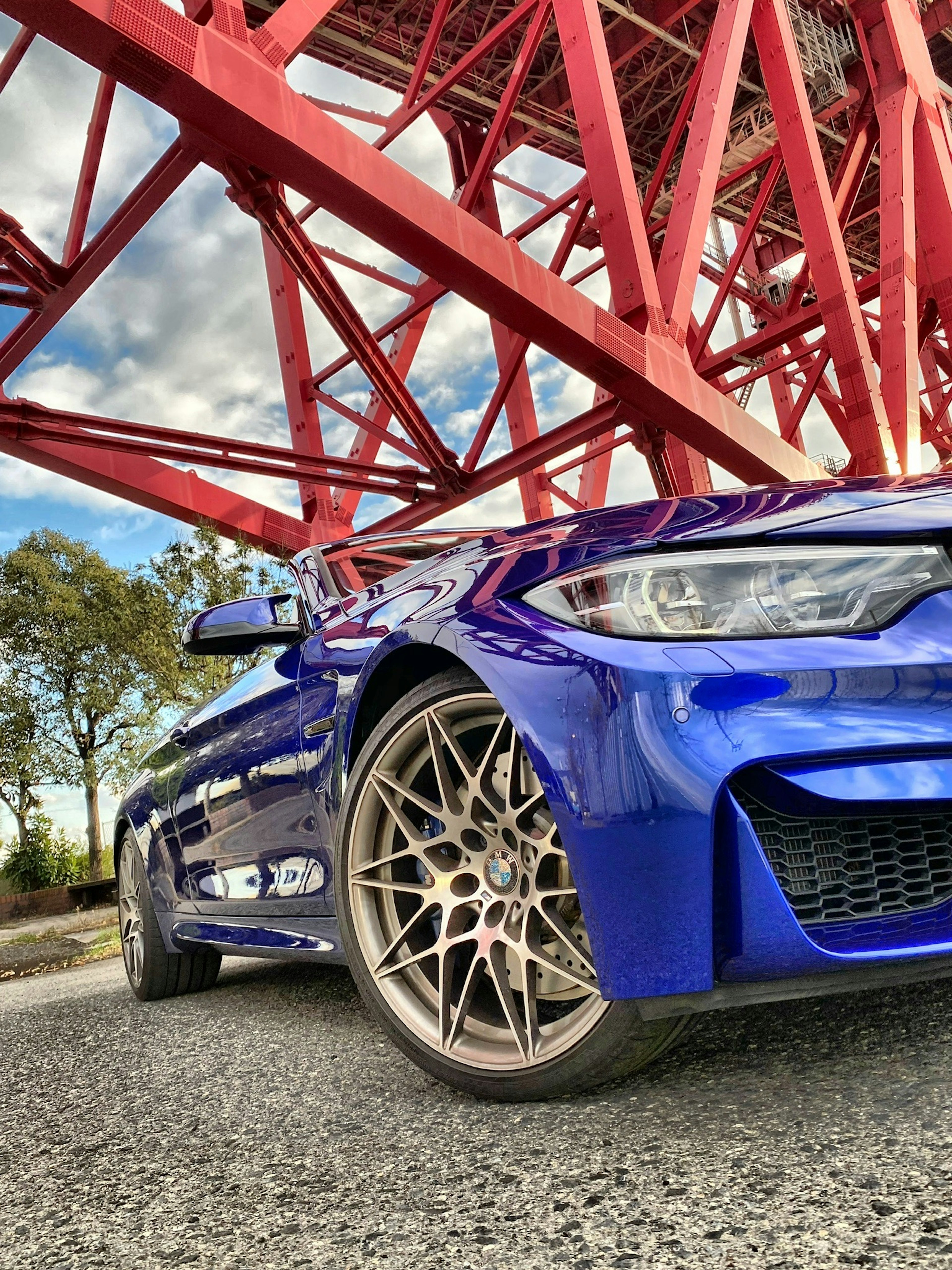 Voiture de sport bleue garée sous un pont rouge