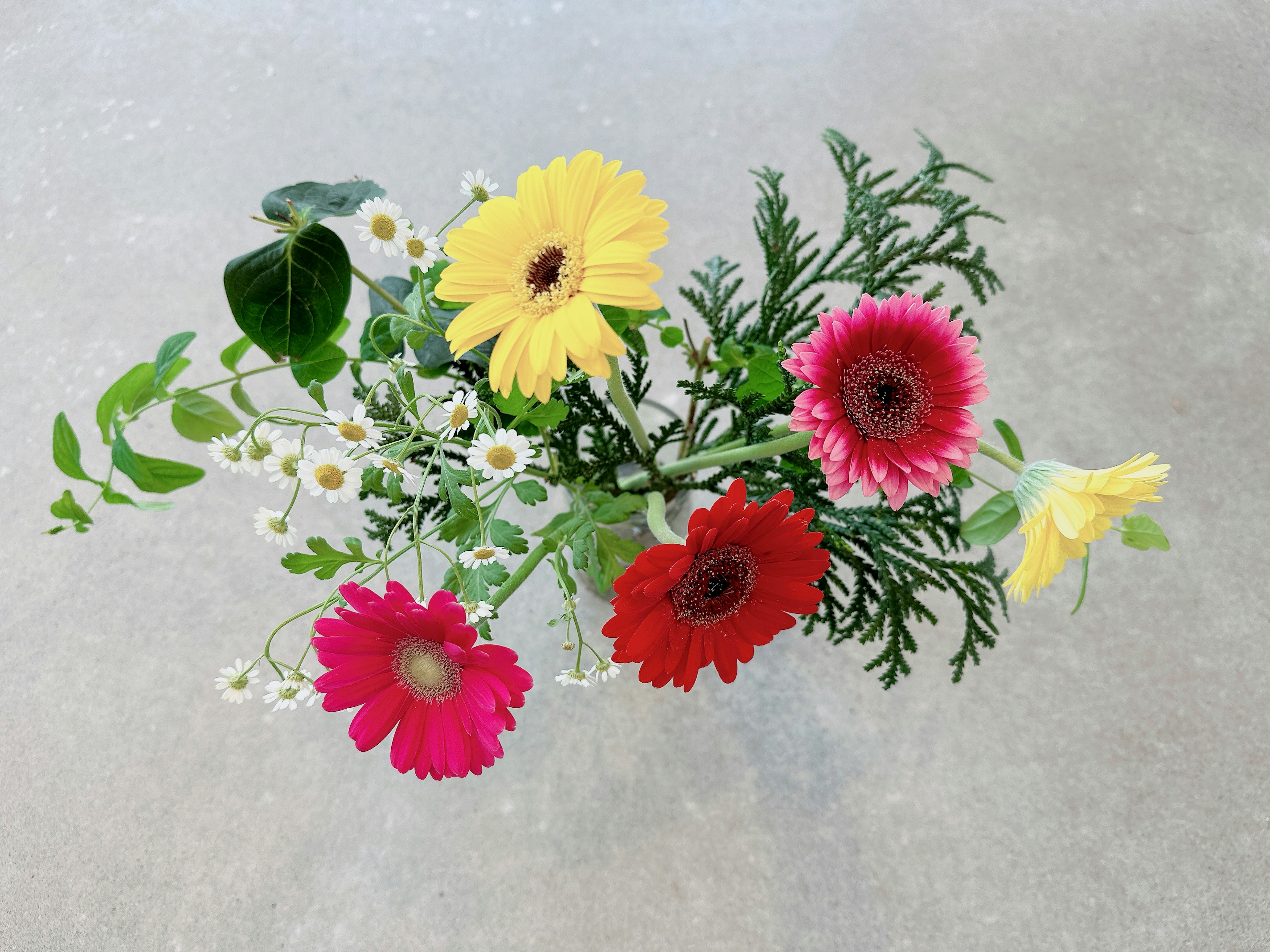 Bouquet coloré avec des gerberas jaunes, rouges et roses et de petites fleurs blanches